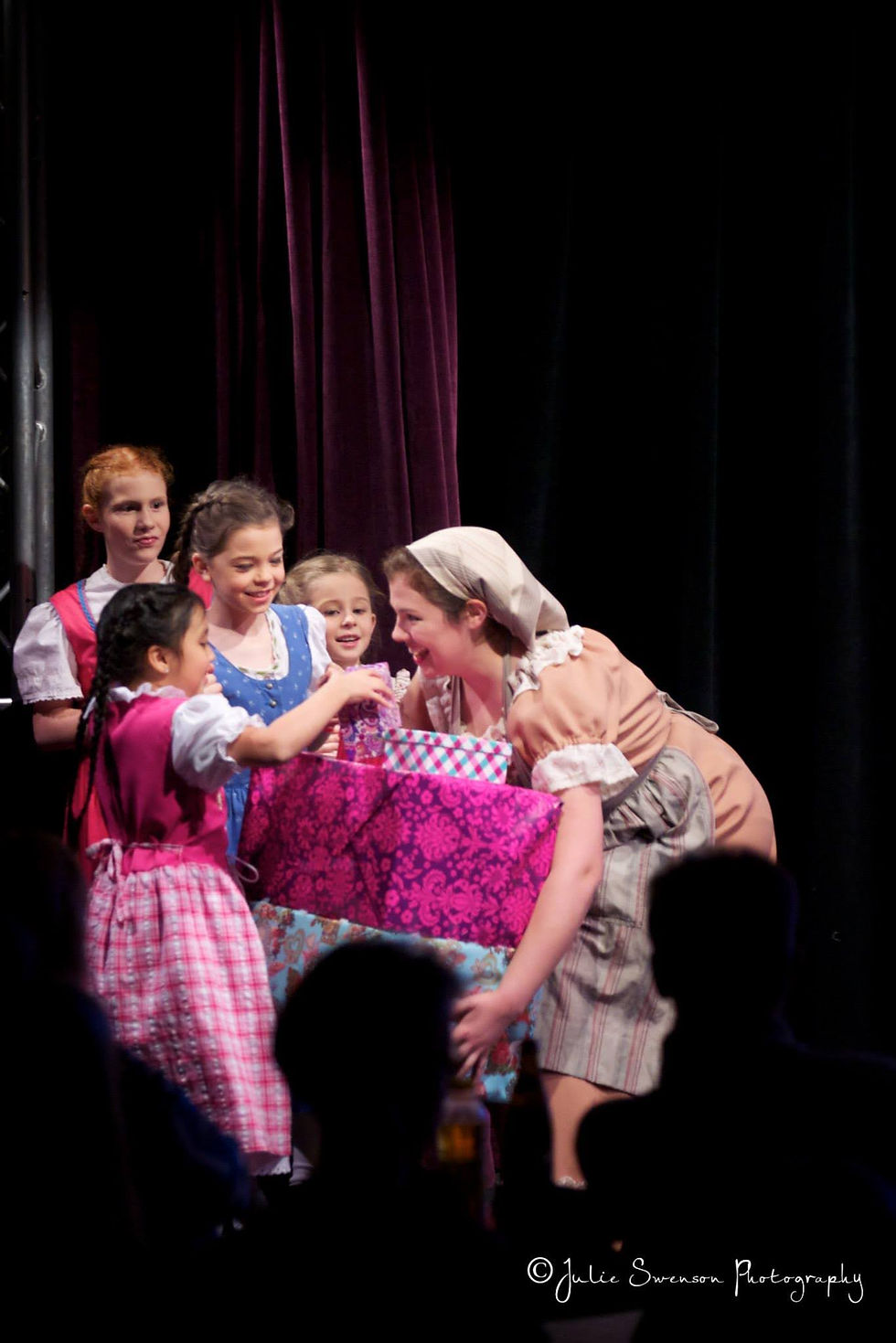 Olivia onstage carrying packages as "Cinderella"
