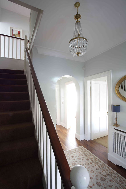 Dublin family home, entrance hallway, wooden floor, traditional rug, chandelier, table lamp, oval mirror