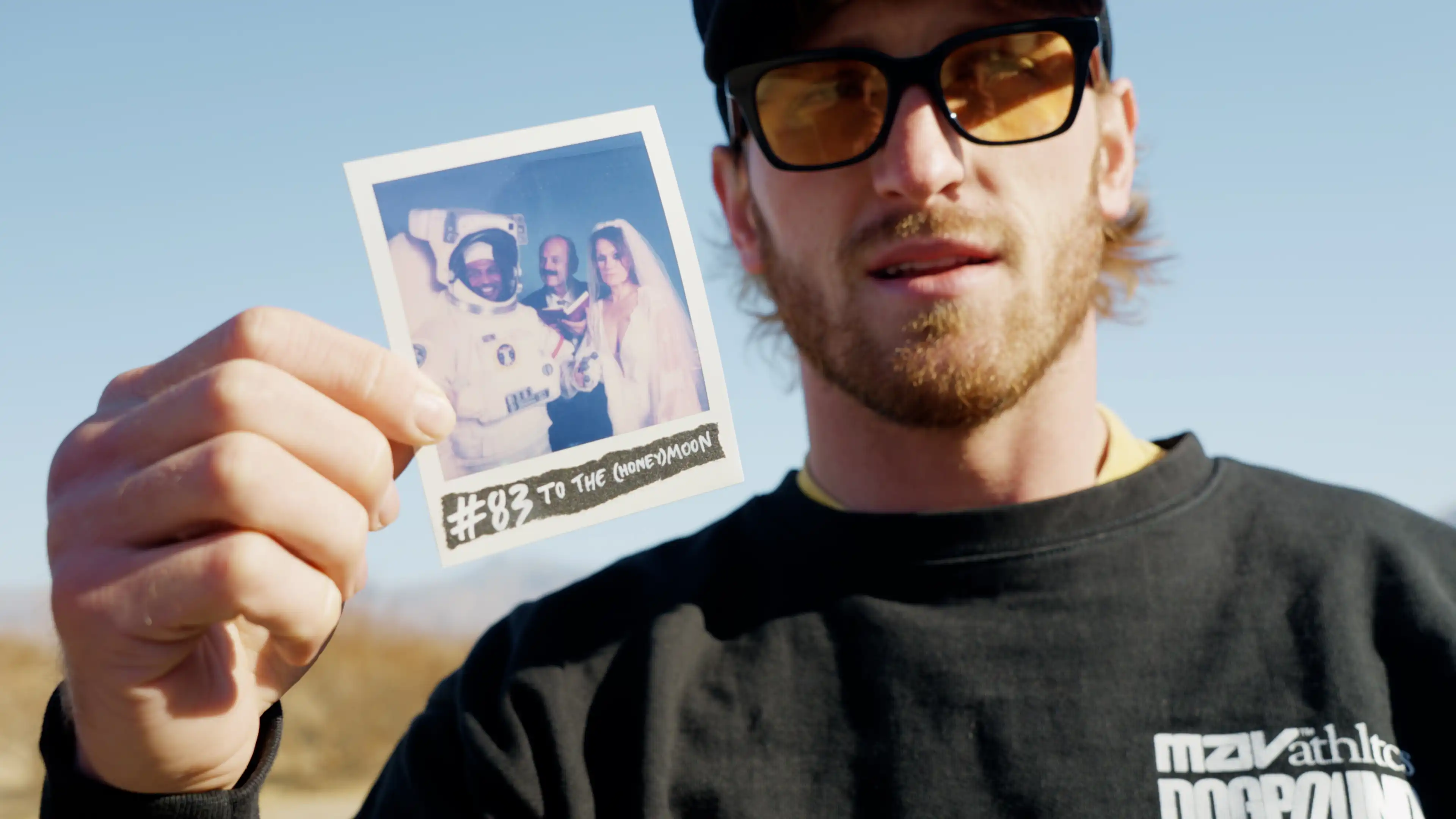 Logan Paul holding No.83 of 99 Originals Polaroid 'TO THE (HONEY) MOON', astronaut wedding crying bride