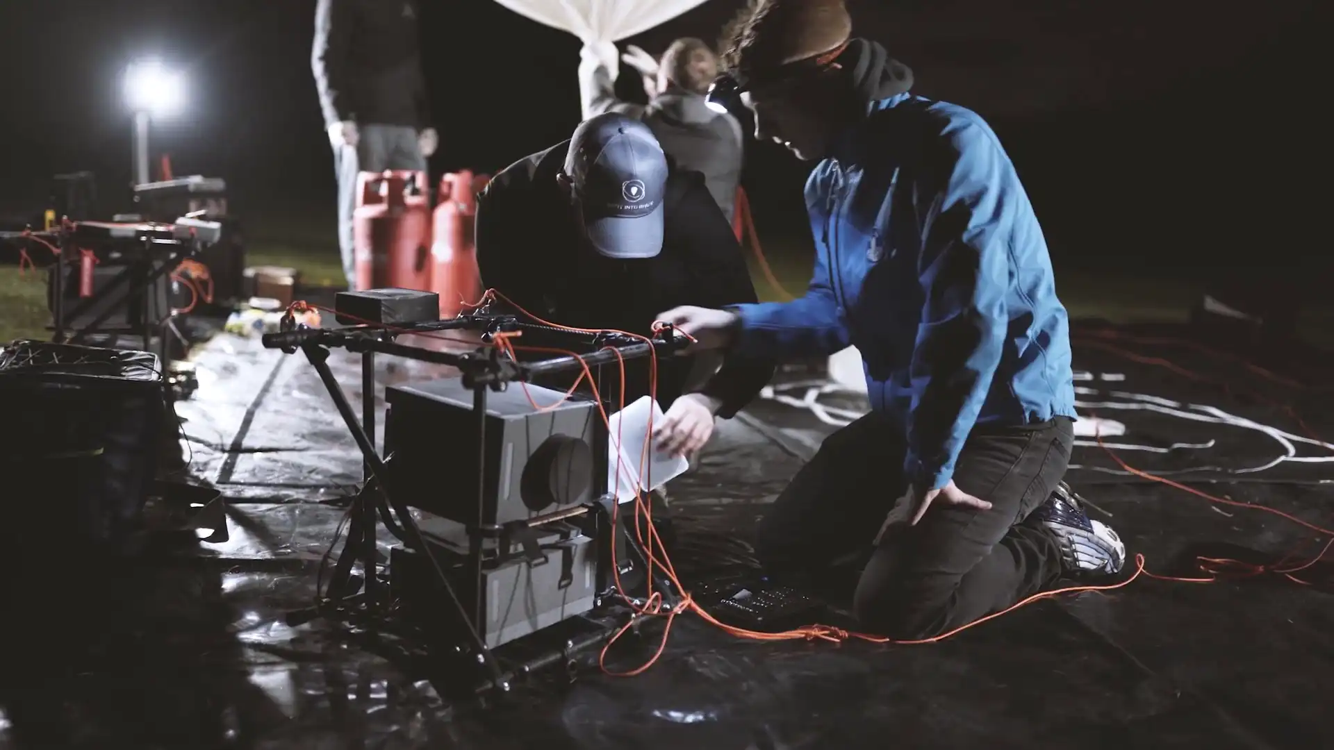 Sent Into Space engineer working on a spacecraft at a launch site at night