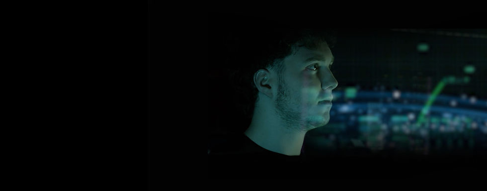 Sent Into Space team member looking at space launch data and visualisations with a blue-green light cast across his face.