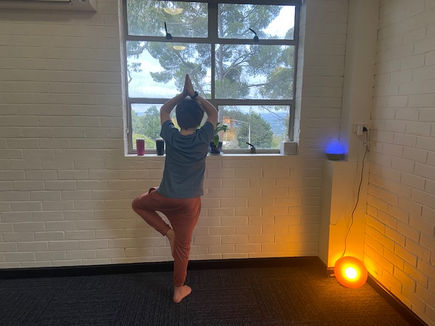 child in tree pose, looking out a window