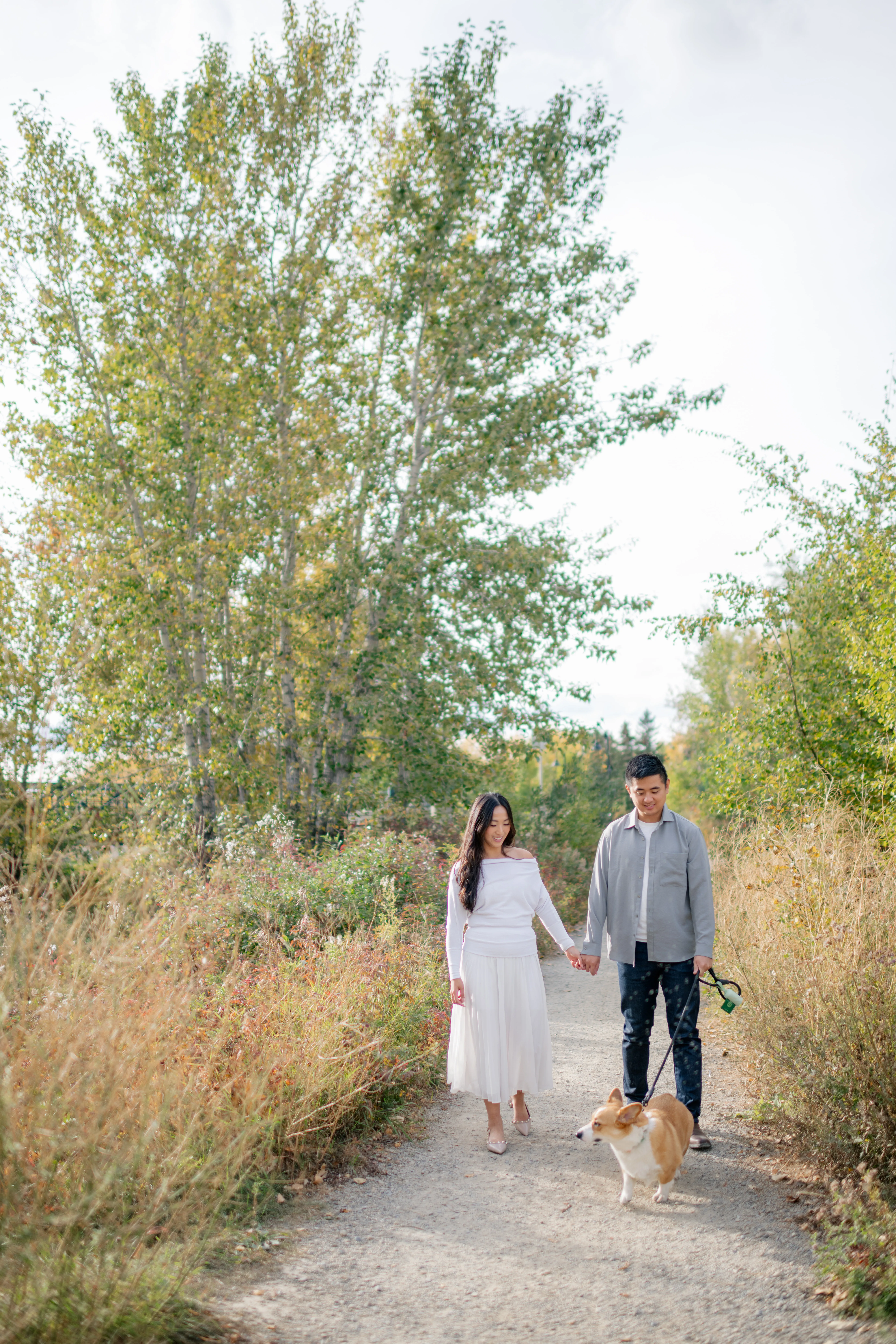 Couple walking along tree-lined pathway at Prince’s Island Park Calgary photoshoot