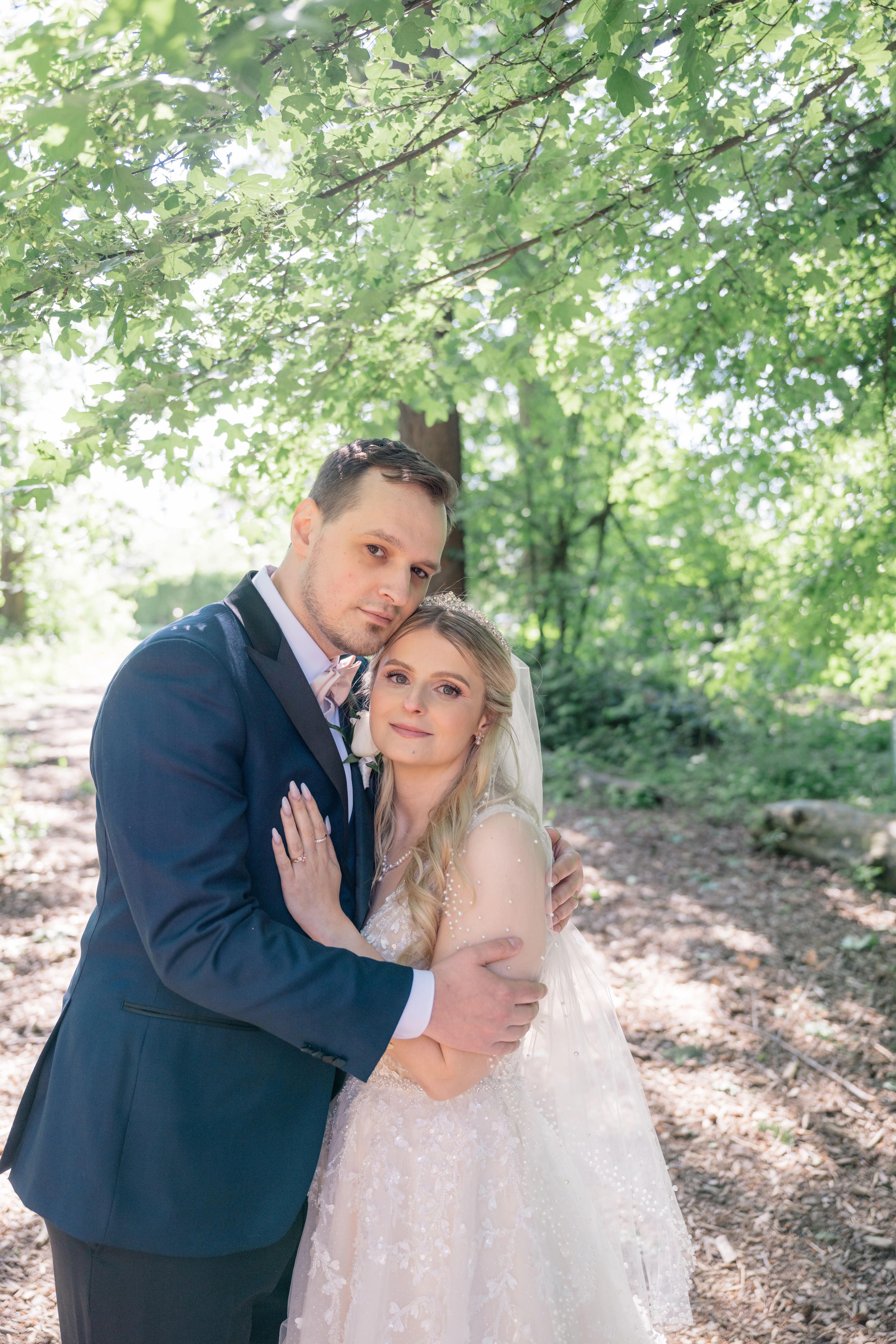 Magical couple portraits in a serene forest setting, with the bride and groom surrounded by towering trees and dappled sunlight