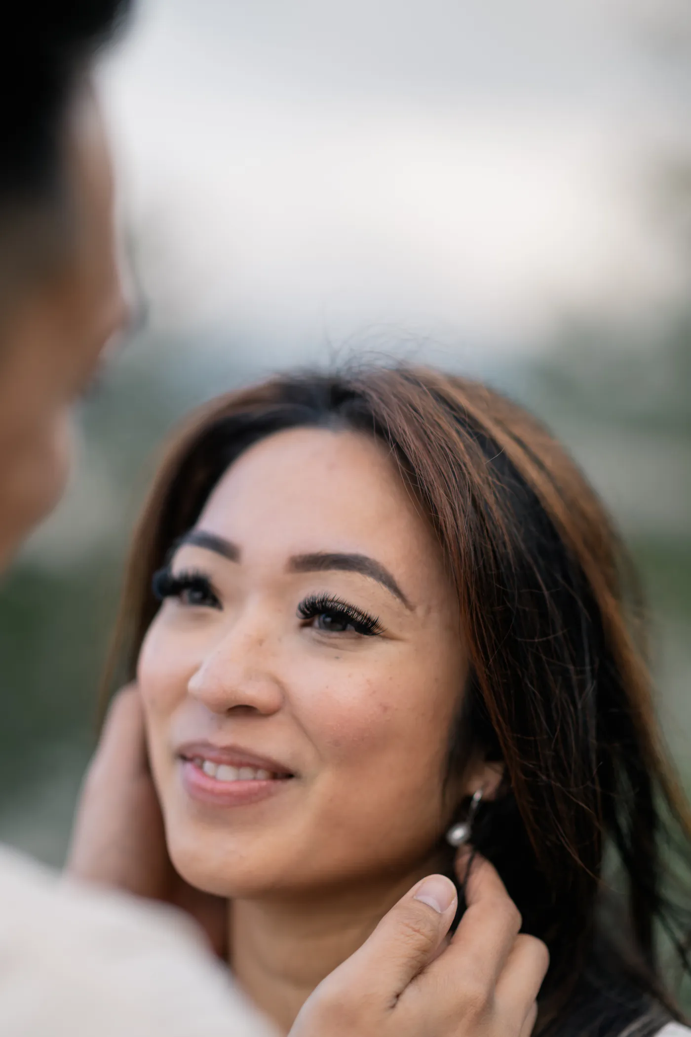 A close-up of a couple smiling at each other, sharing a quiet, joyful moment during their engagement session