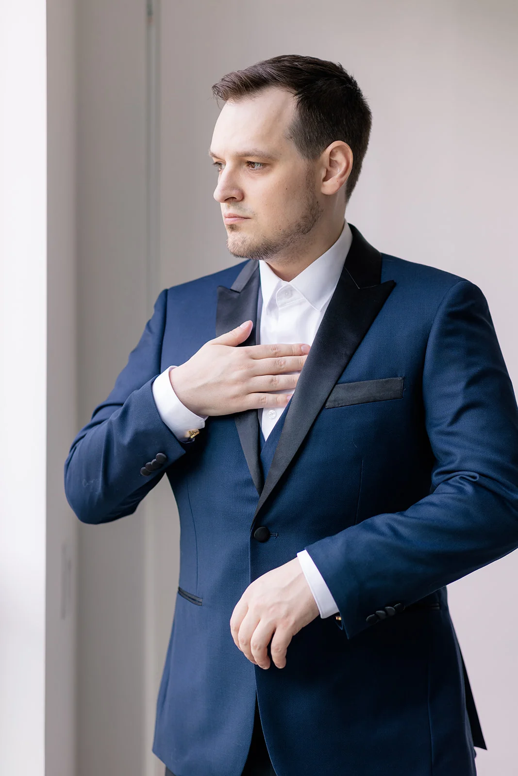 Groom adjusting his tie in front of a mirror, preparing for the wedding ceremony