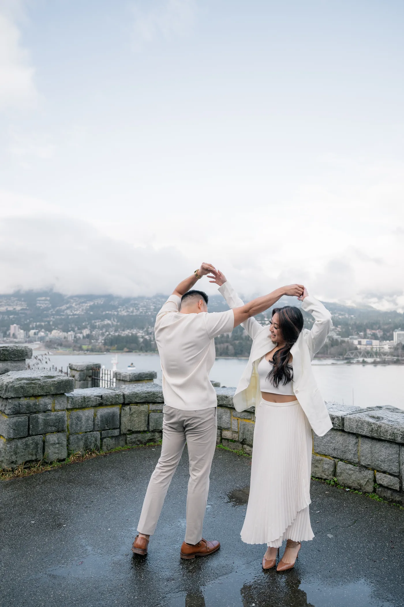 A couple shares an intimate embrace with misty Vancouver mountains in the background, creating a soft, romantic engagement portrait.