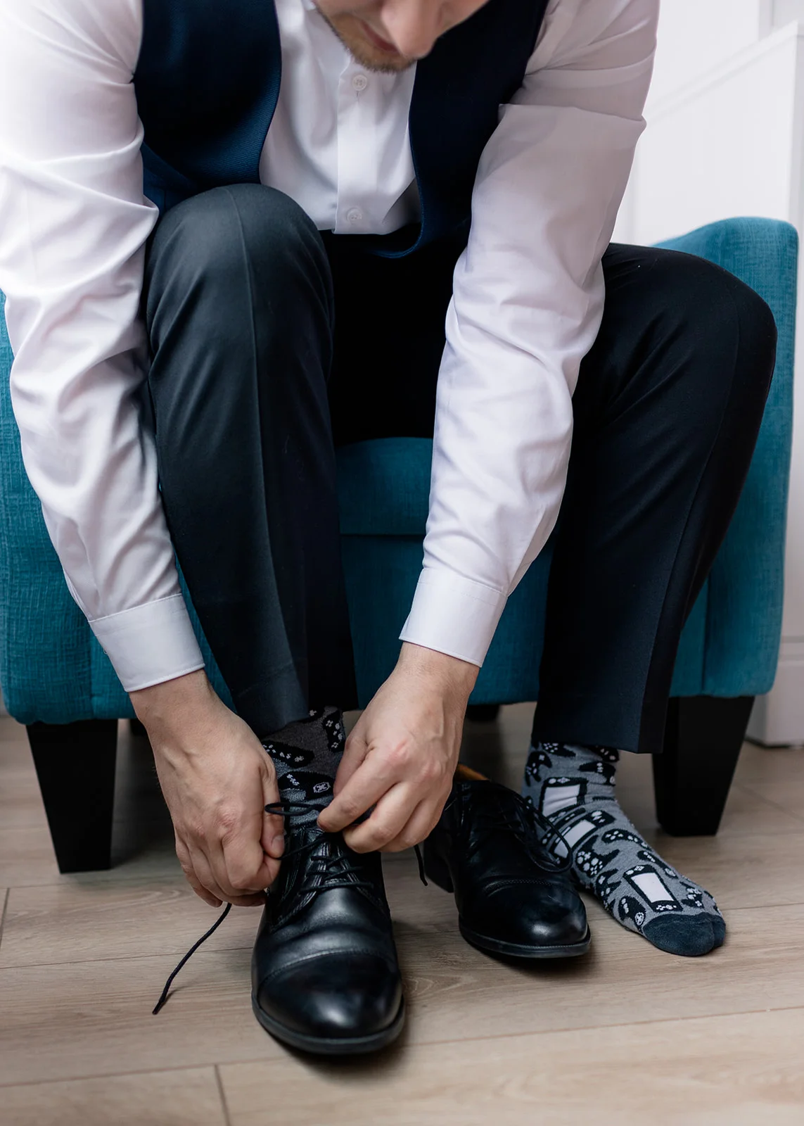 Groom putting on his polished shoes, completing his wedding day look.