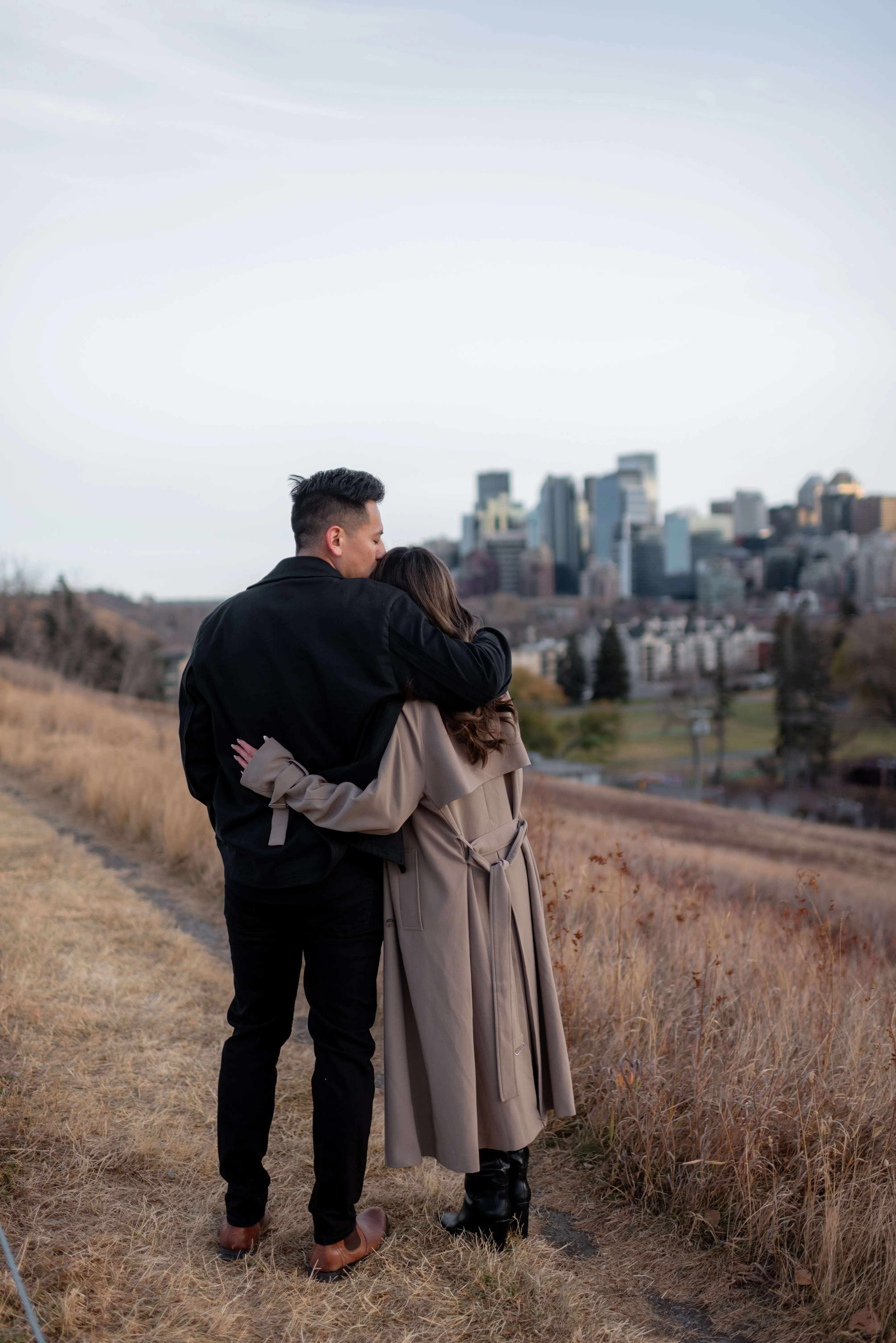 Couple standing together overlooking the Calgary skyline during an engagement photoshoot at SAIT Polytechnic P1 parkade