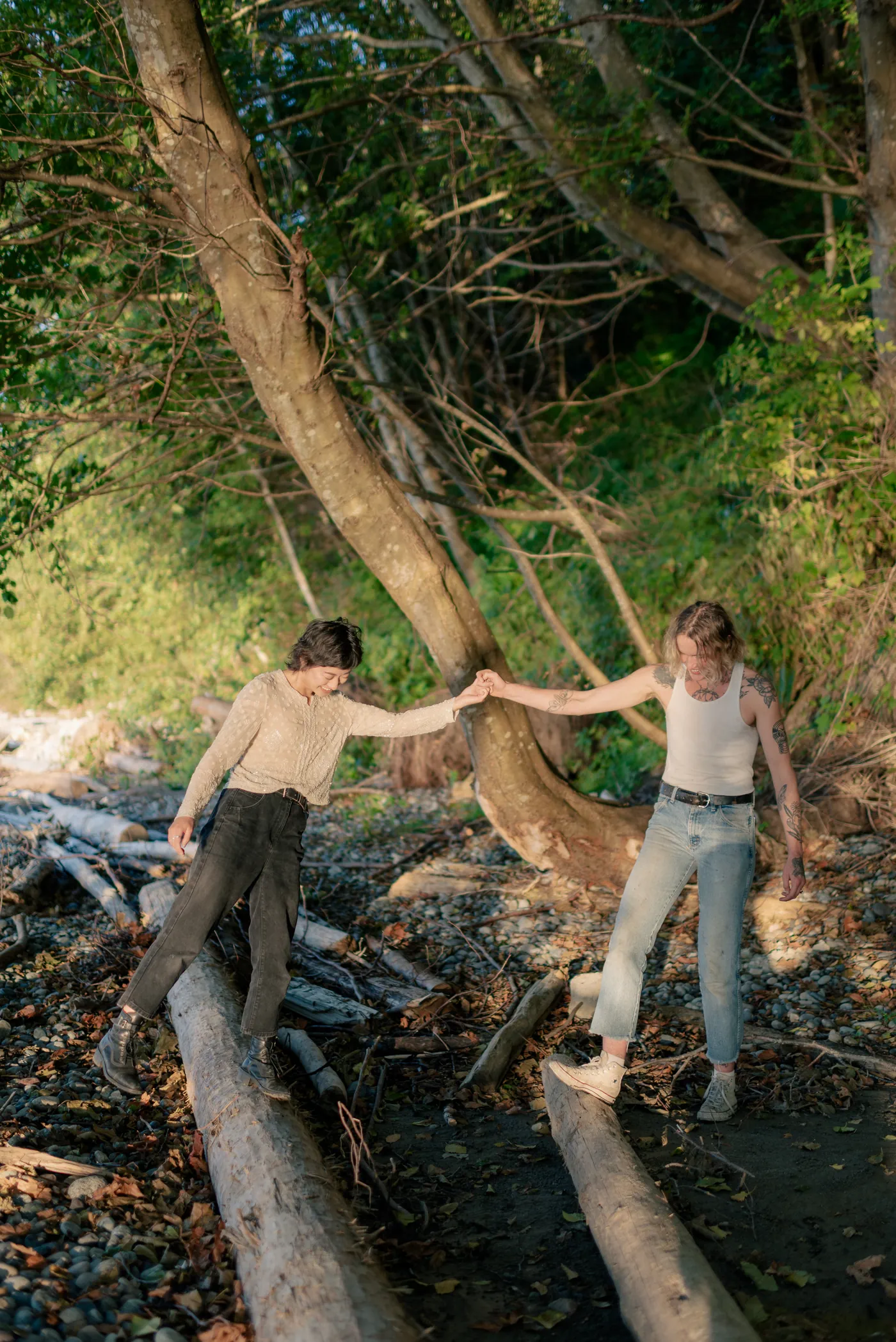 Newly engaged queer couple walking along the shore, celebrating their love. A dreamy and intimate engagement session on a scenic Canadian beach.