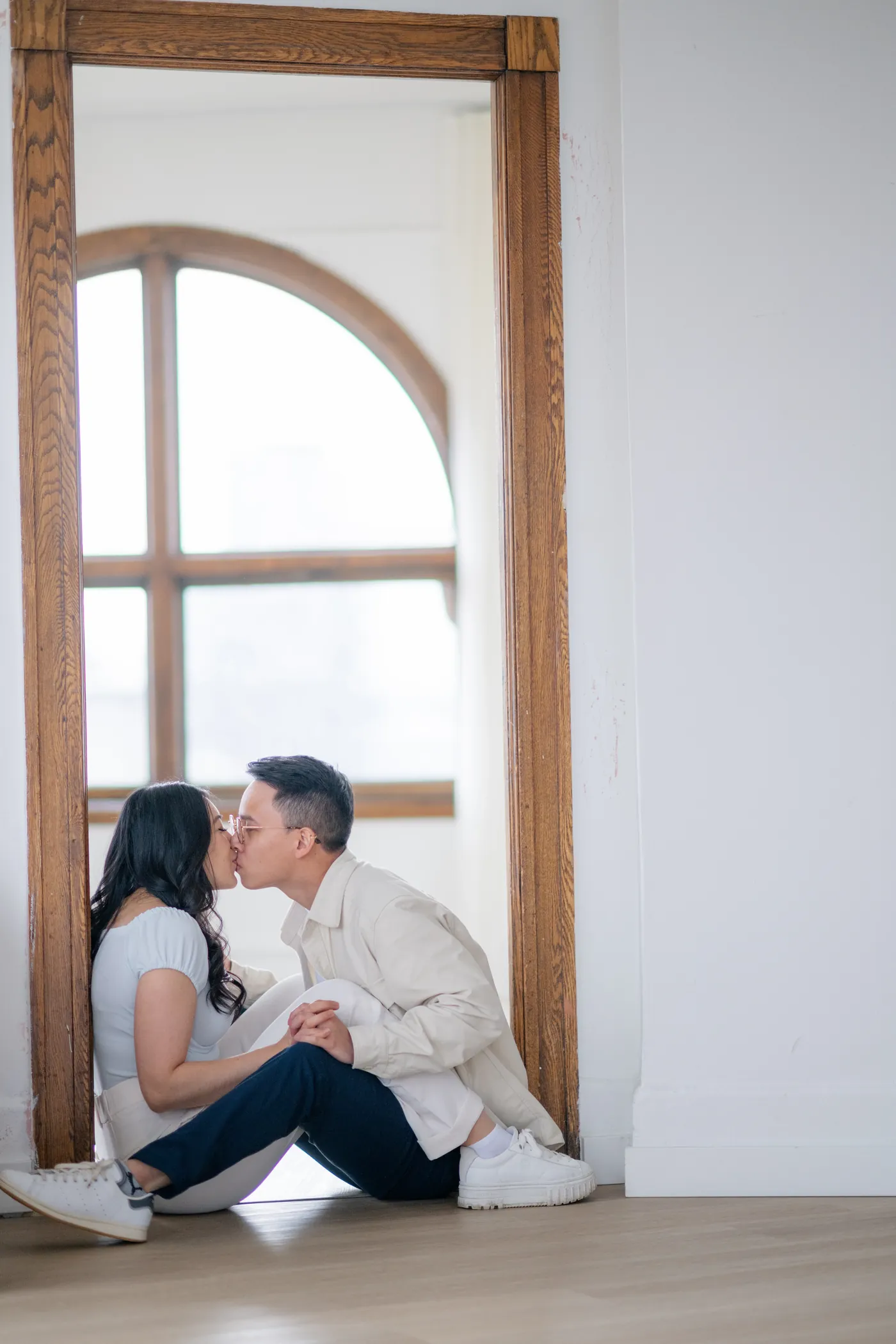 Artistic photo of engaged couple framed by The Covet Studio's iconic arched door, perfect for indoor engagement photography.