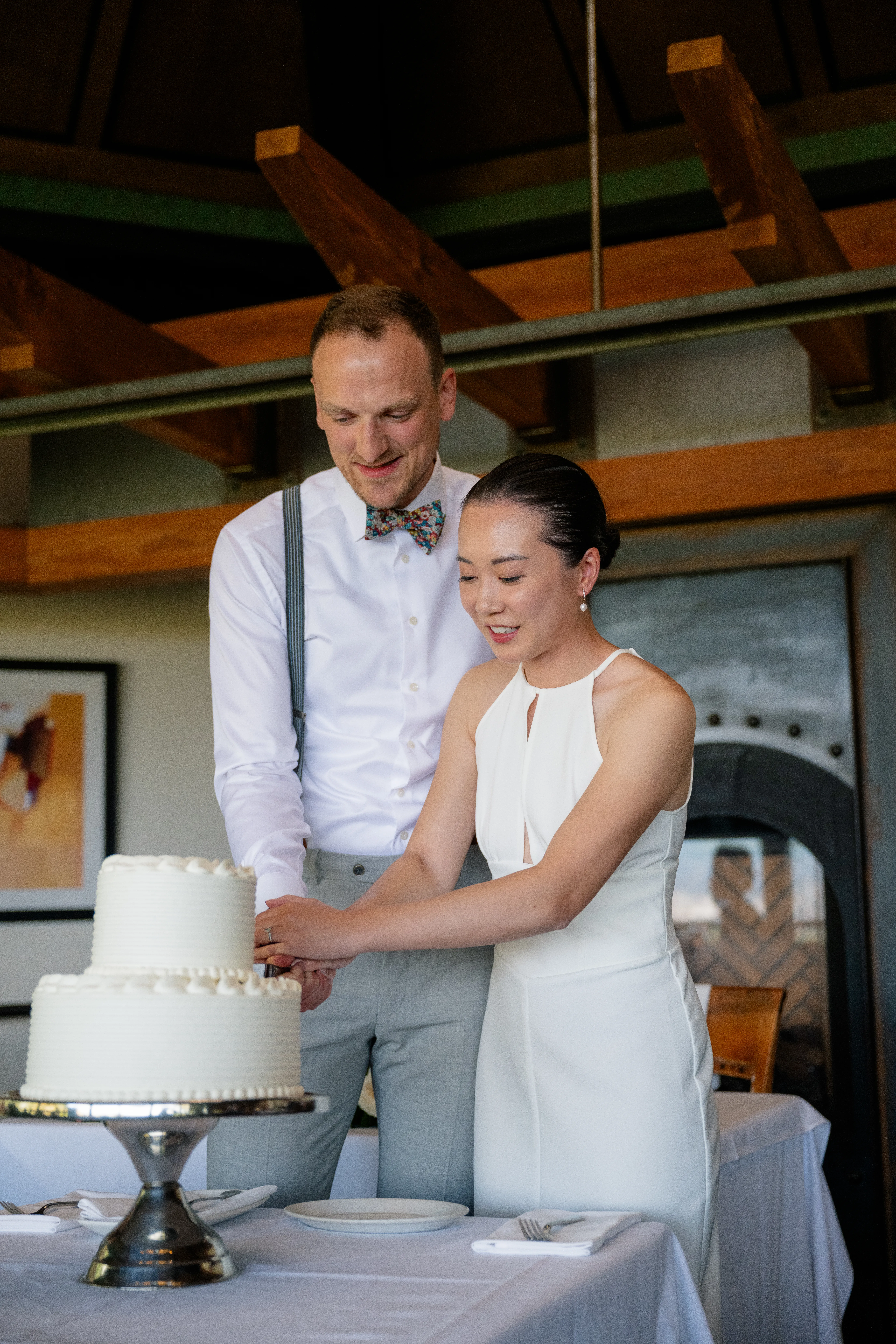 Bride and groom smiling as they cut the wedding cake together during the reception.