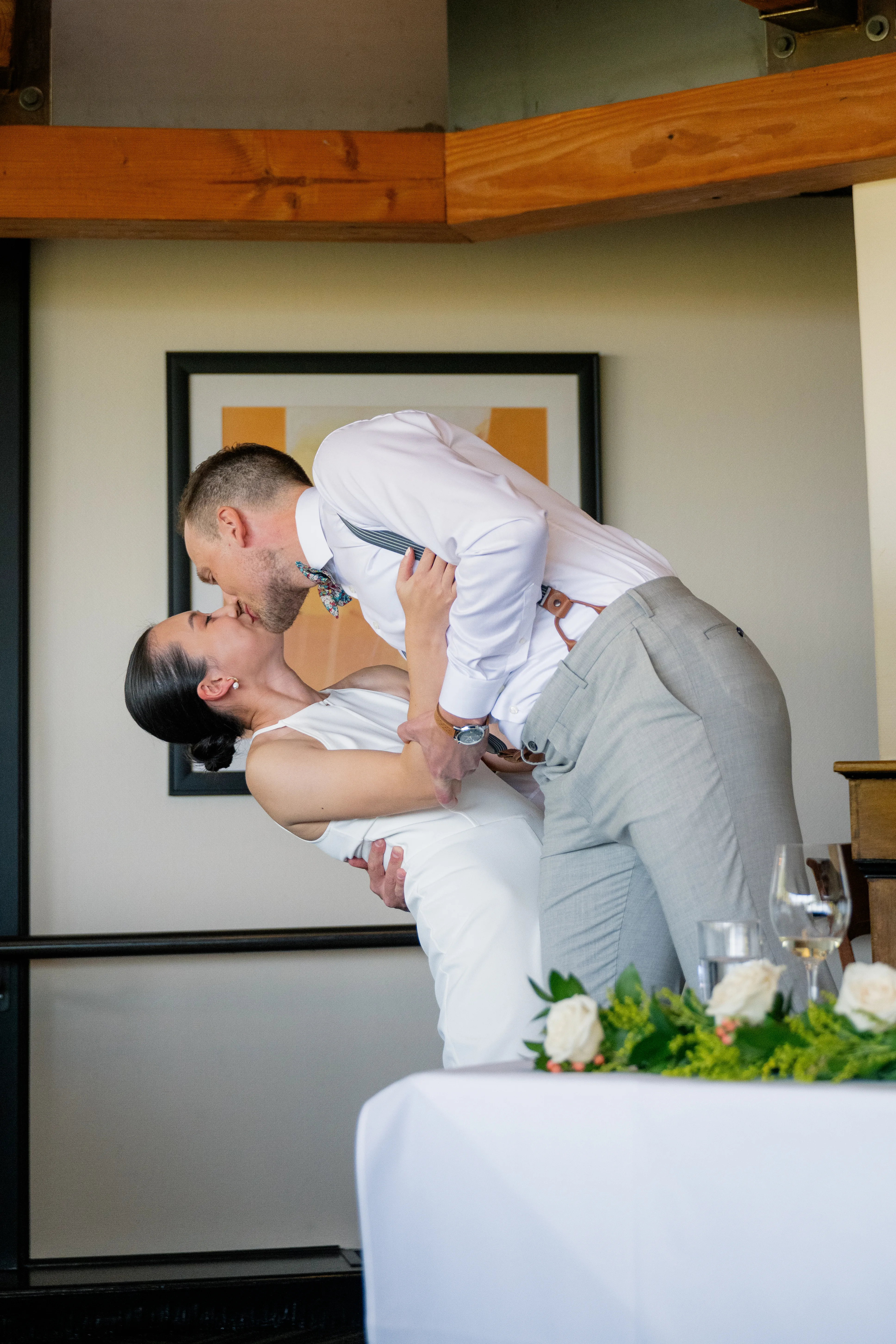 Bride and groom sharing a kiss during the wedding reception, with the bride leaning backward as they embrace