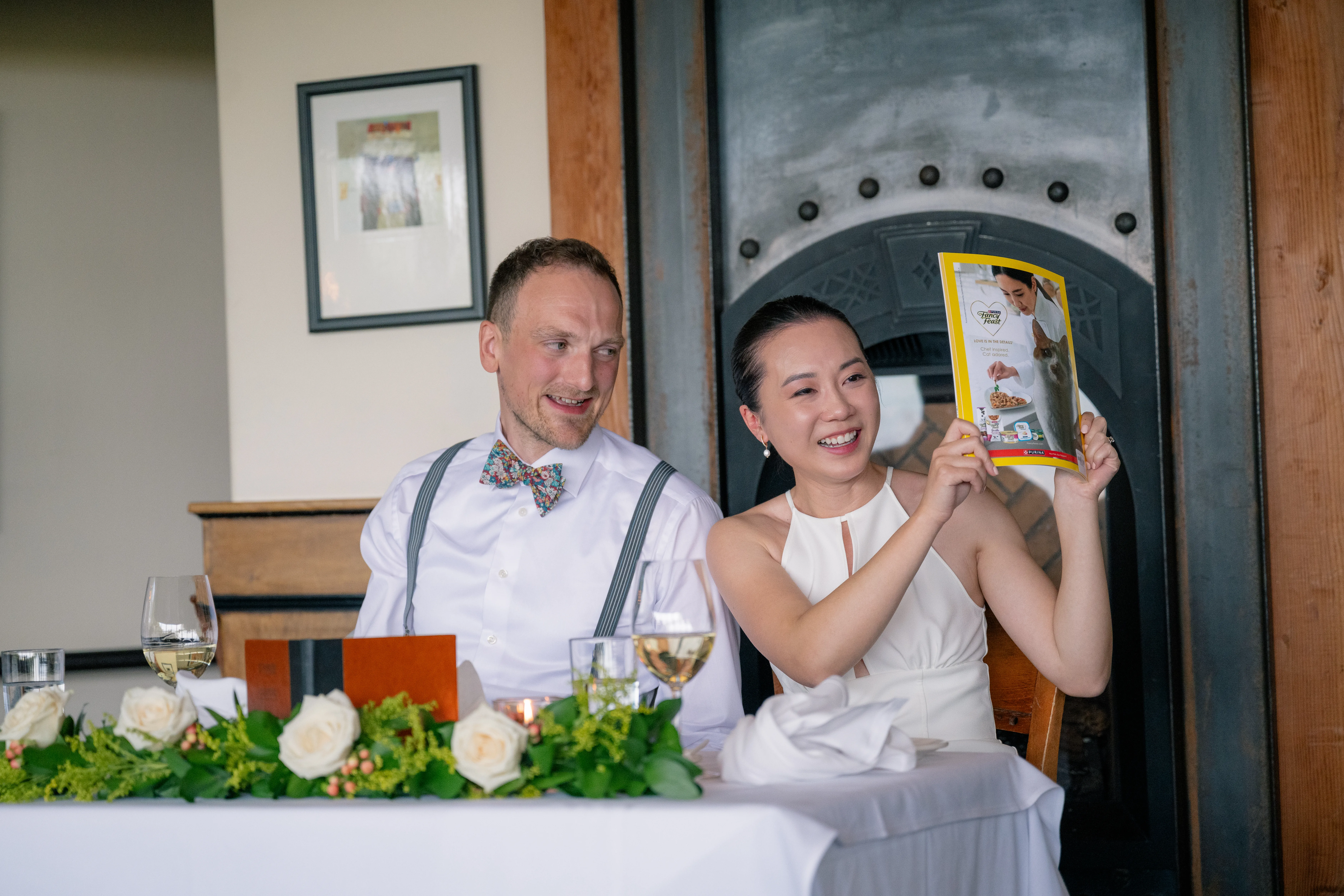 Family member standing and giving a speech at the wedding reception, while the bride and groom listen with smiles.