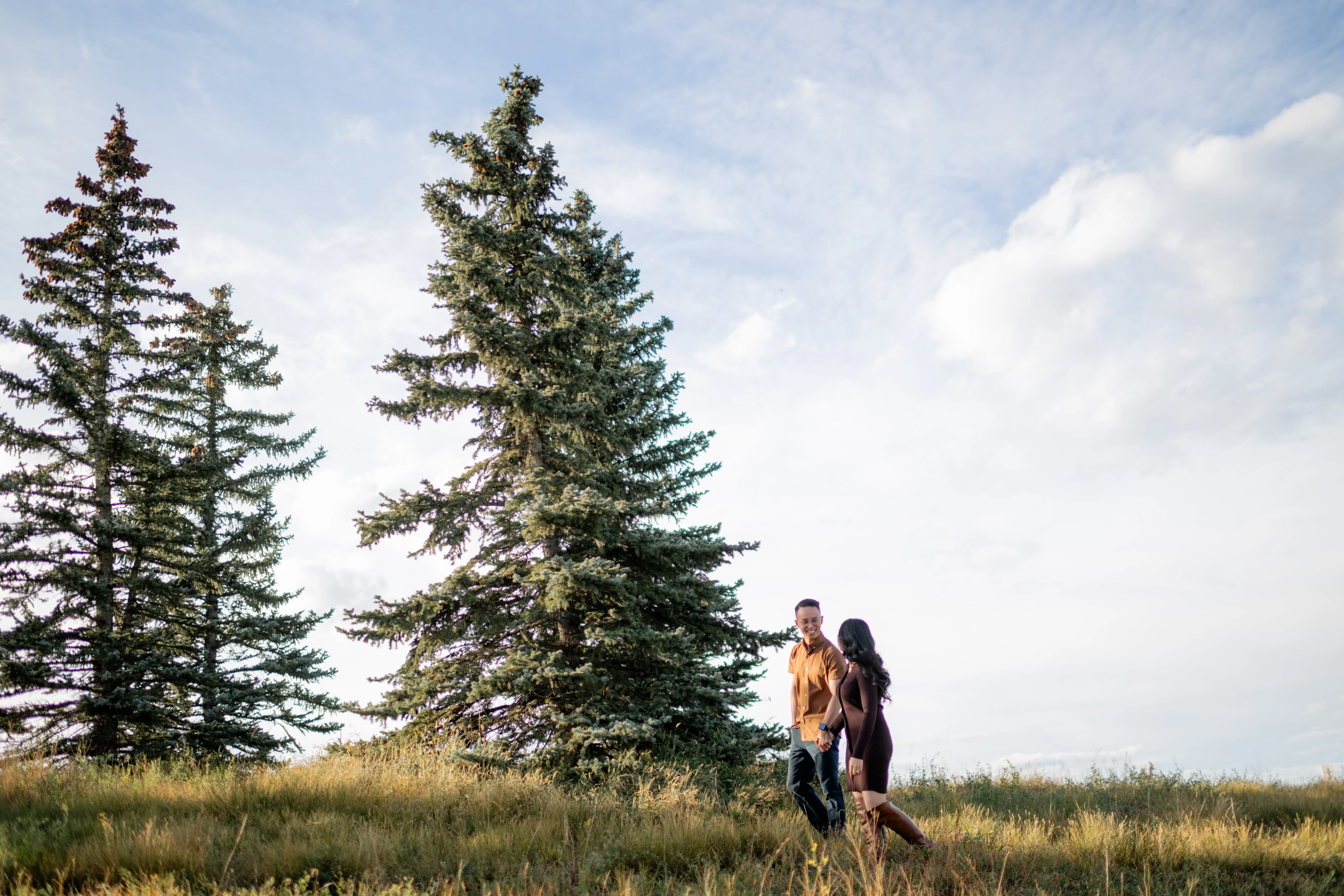 Couple walking together through tall grass at Evamy Ridge in Calgary