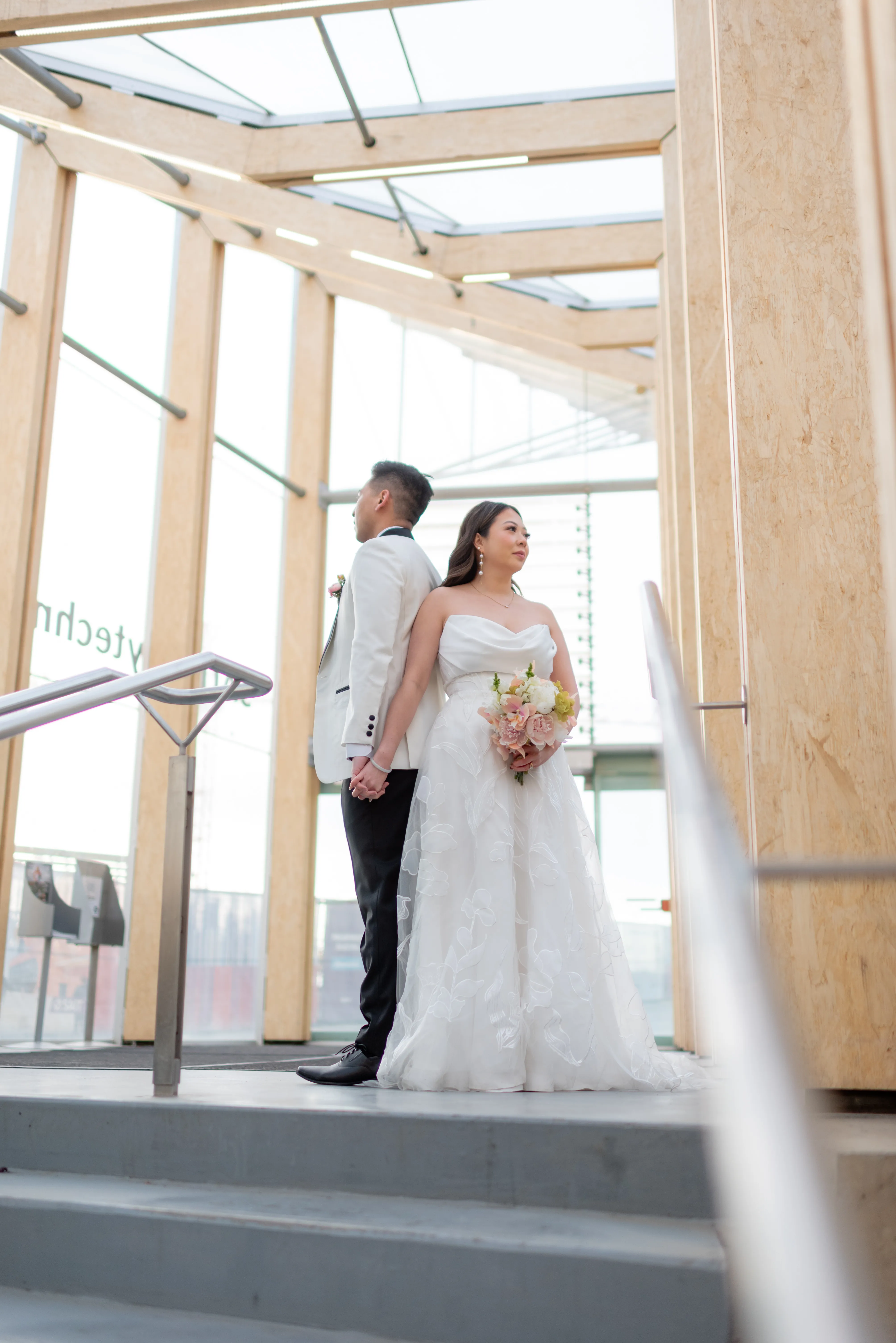 Wide shot of bride and groom framed by concrete and glass at SAIT Parkade