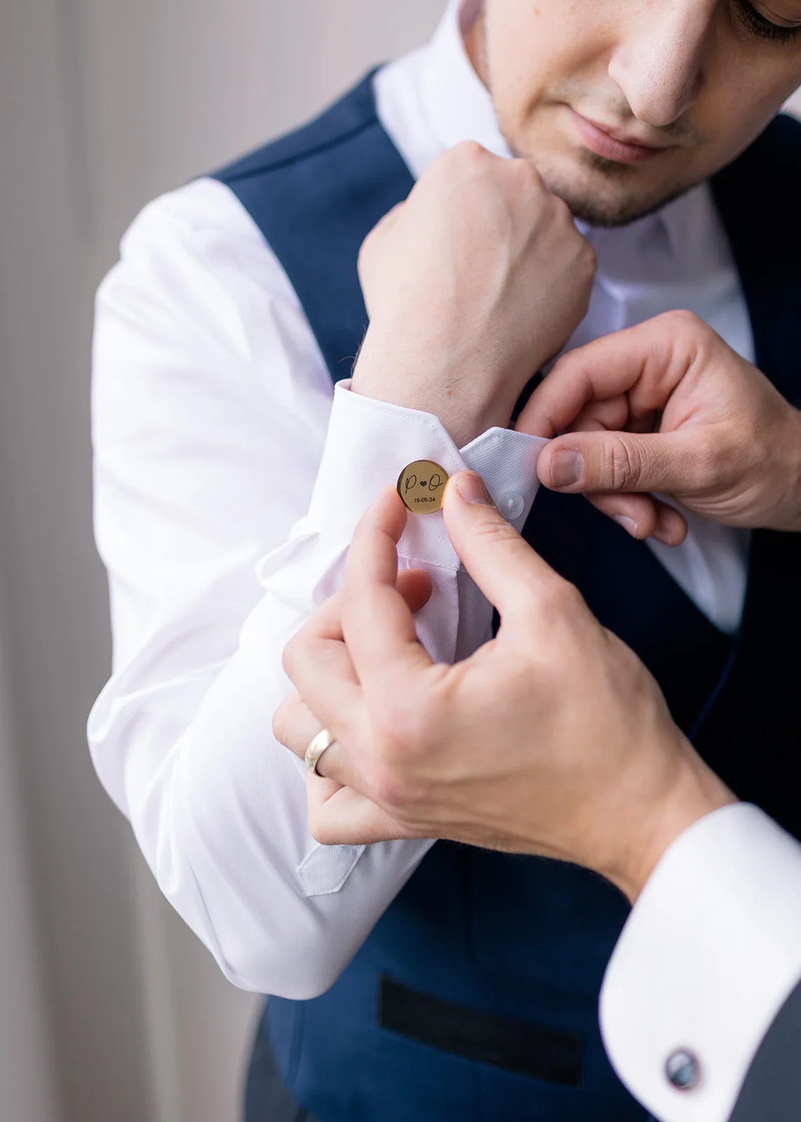 Close-up of the groom fastening his cufflinks, adding a personal touch to his wedding attire