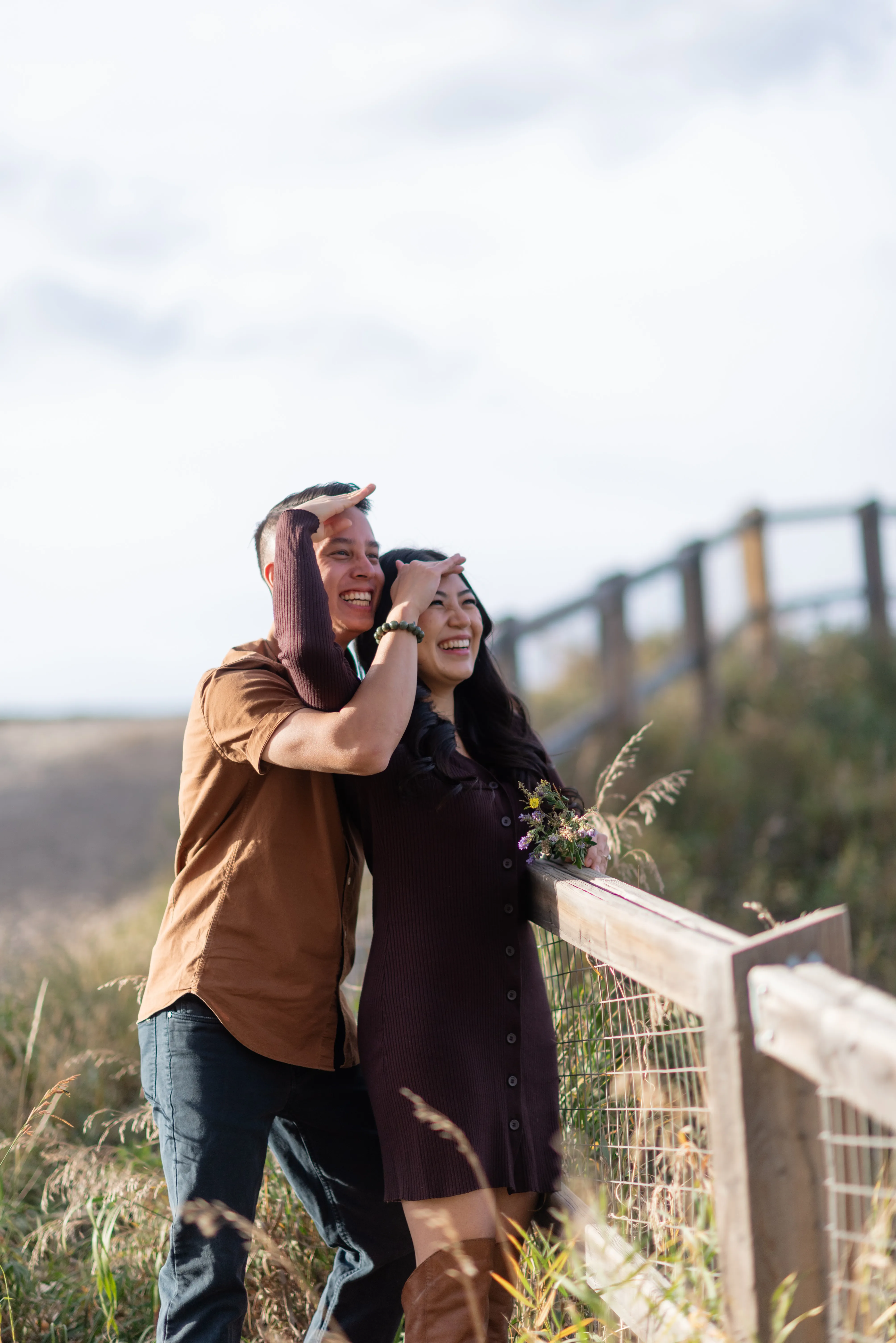 Candid engagement phot of couple looking out towards Elbow River in Calgary during fall