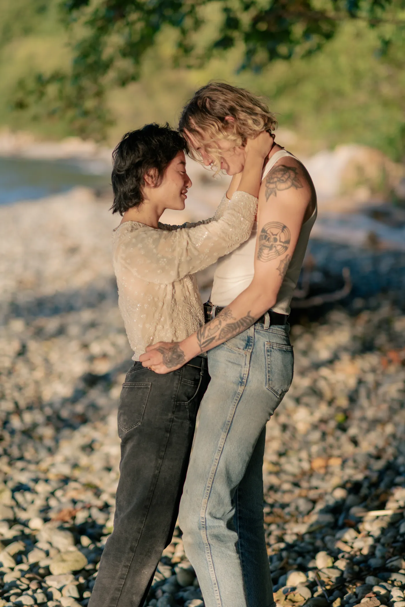 Newly engaged queer couple walking along the shore, celebrating their love. A dreamy and intimate engagement session on a scenic Canadian beach.
