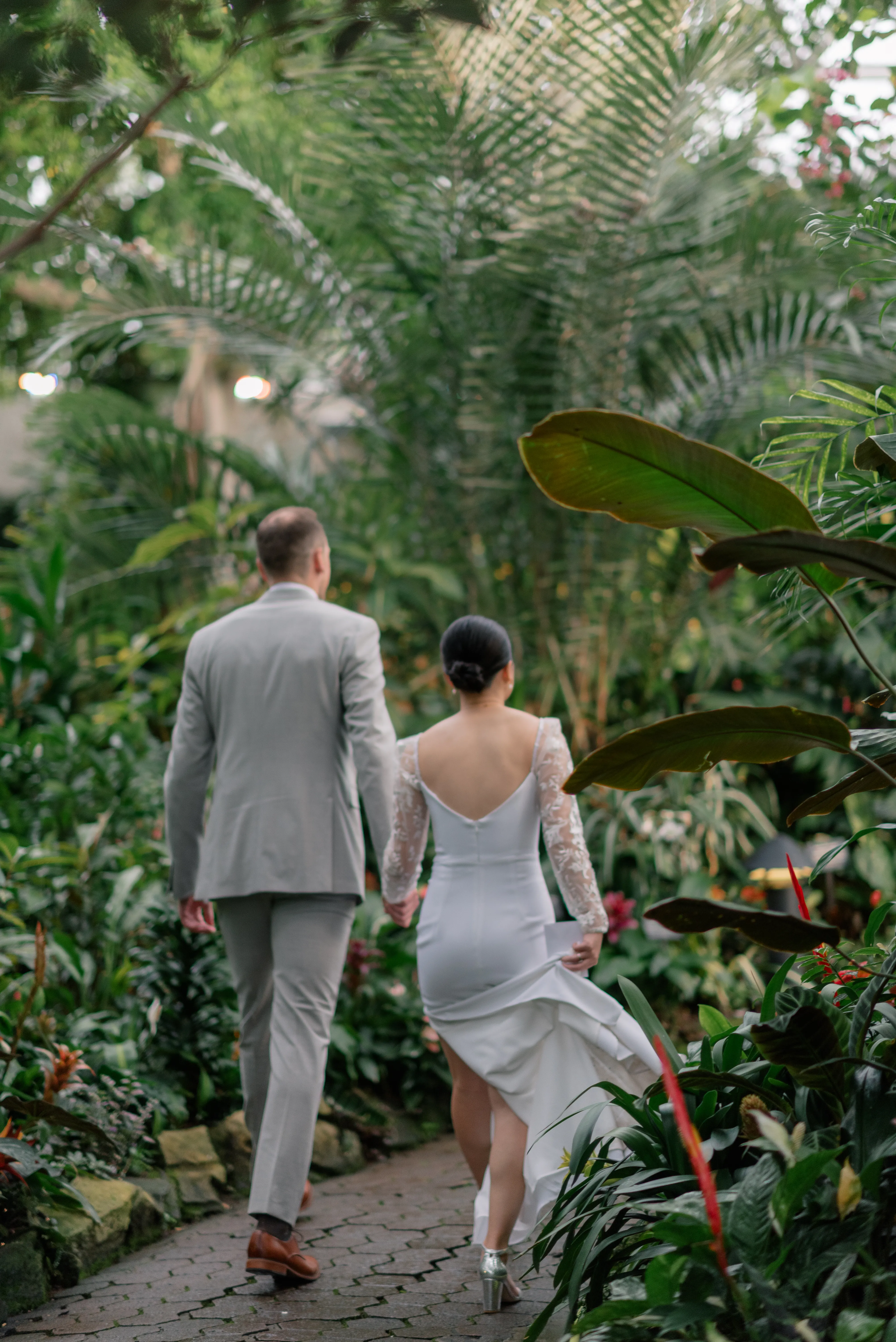 Bride and groom embracing among the tropical plants inside Bloedel Conservatory, surrounded by lush greenery