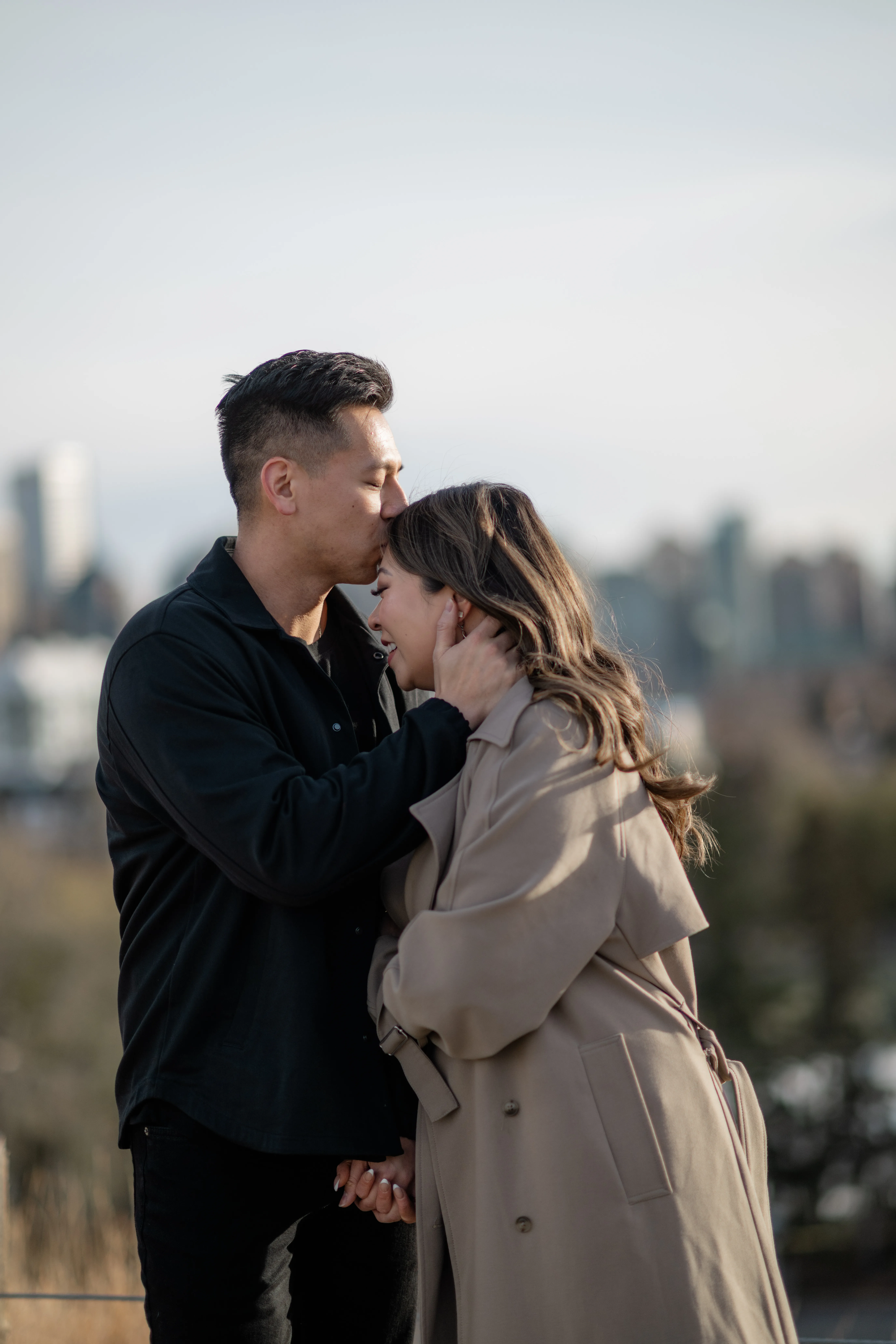 Romantic engagement portrait of couple embracing with Calgary skyline behind them