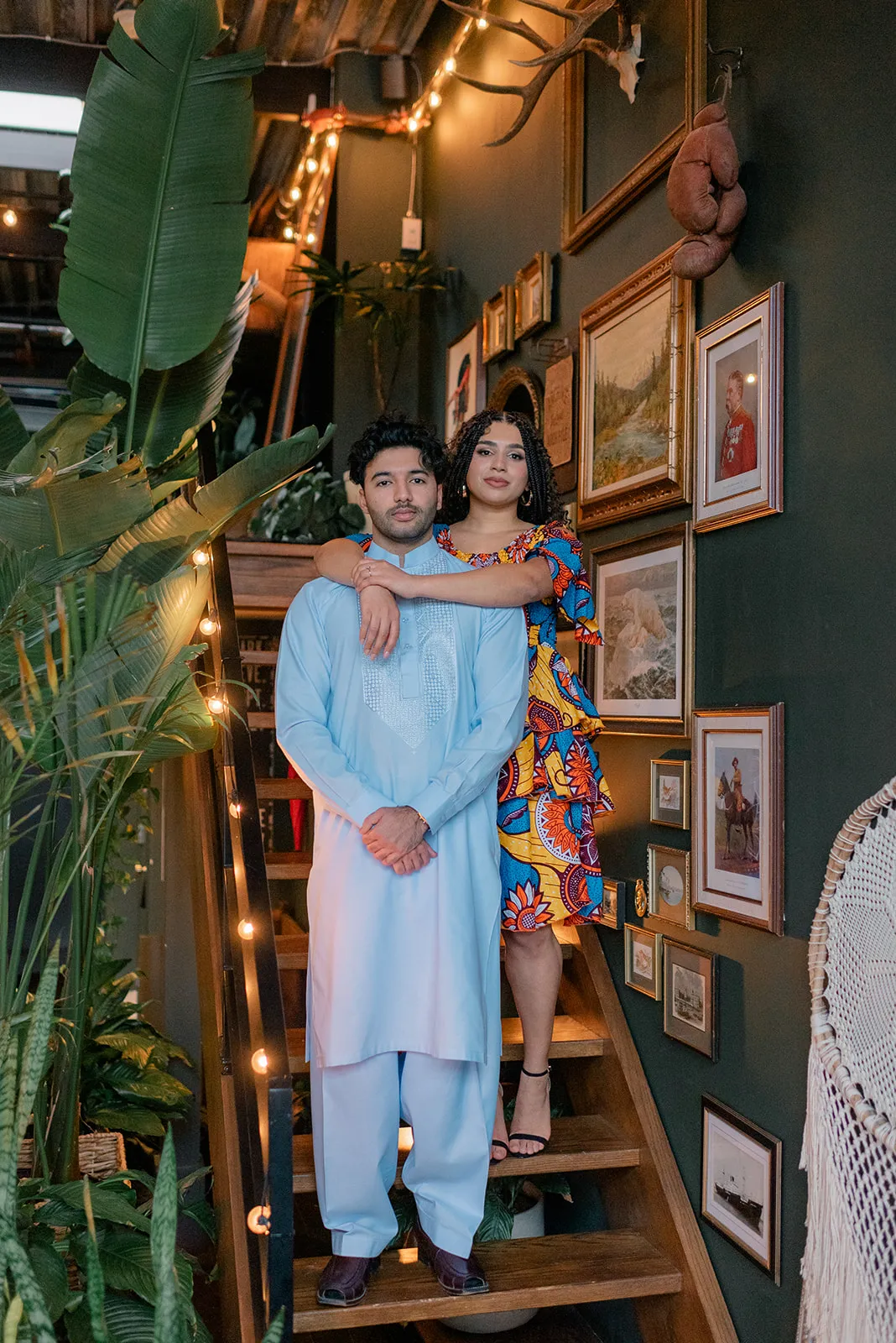 Couple sharing a laugh under the indoor greenery at Loft Garden Oasis, highlighting vibrant cultural attire and intimate moments