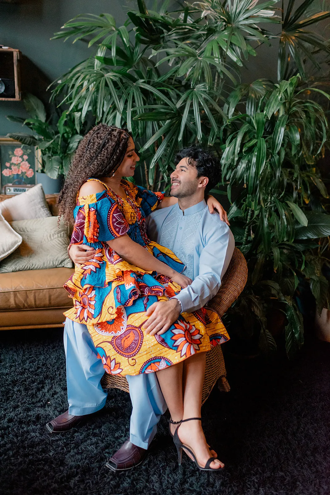 Couple sharing a laugh under the indoor greenery at Loft Garden Oasis, highlighting vibrant cultural attire and intimate moments