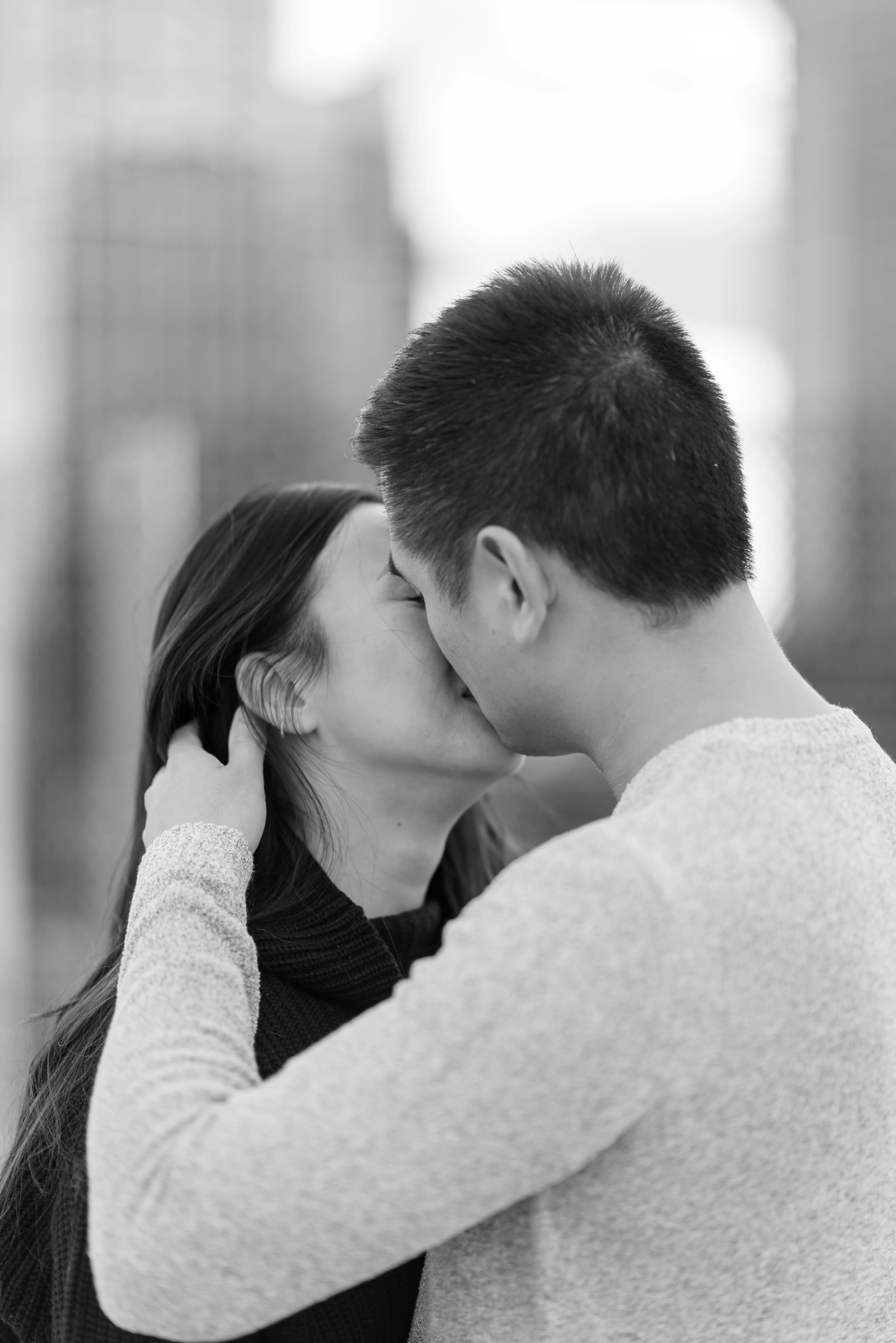 A couple shares a gentle kiss during sunset at couple photos at Platform Parkade rooftop with Calgary skyline