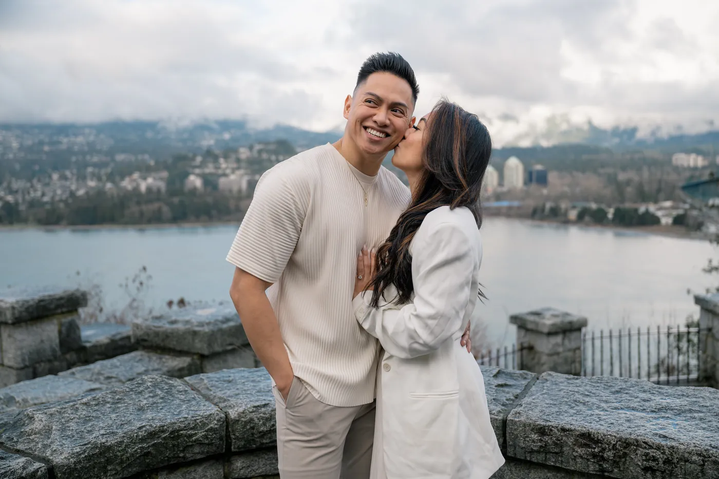 A black-and-white image of a couple embracing while gazing at the Lions Gate Bridge, symbolizing strength and connection in their love story.