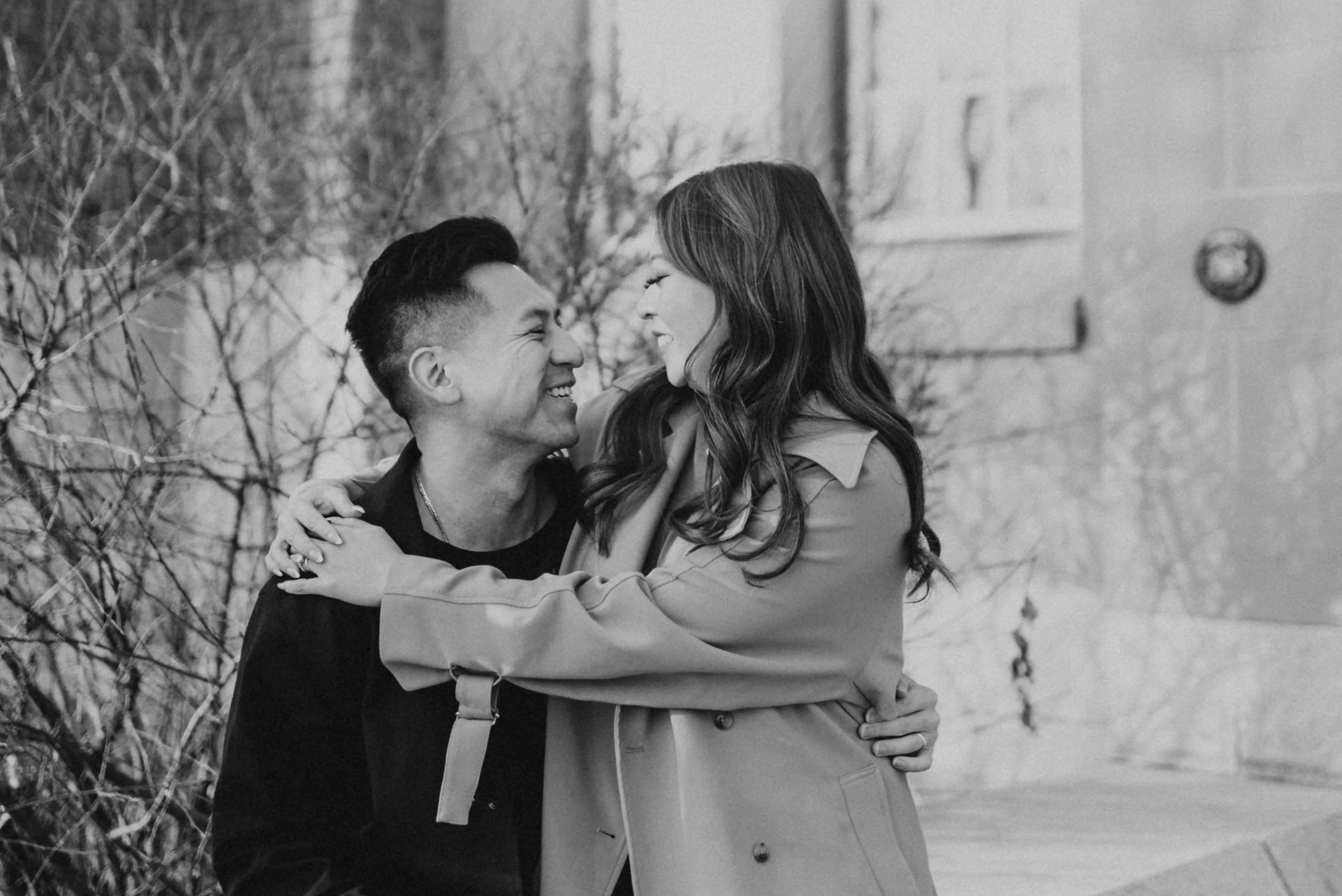 Black and white candid engagement photo of couple sitting together at Heritage Hall in Calgary
