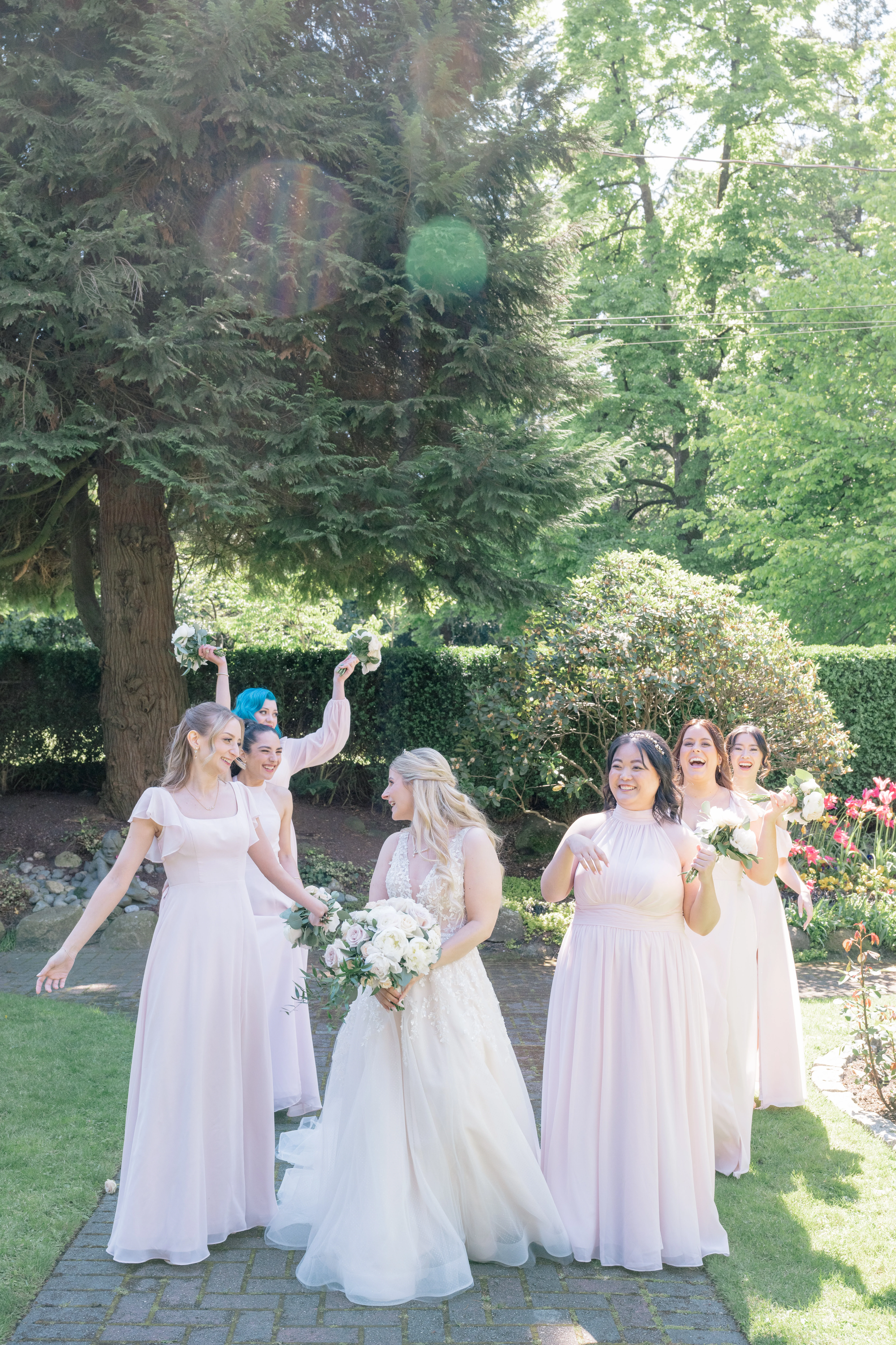 Bride laughing with her six bridesmaids in coordinating dresses, showcasing the strong bond and camaraderie among friends