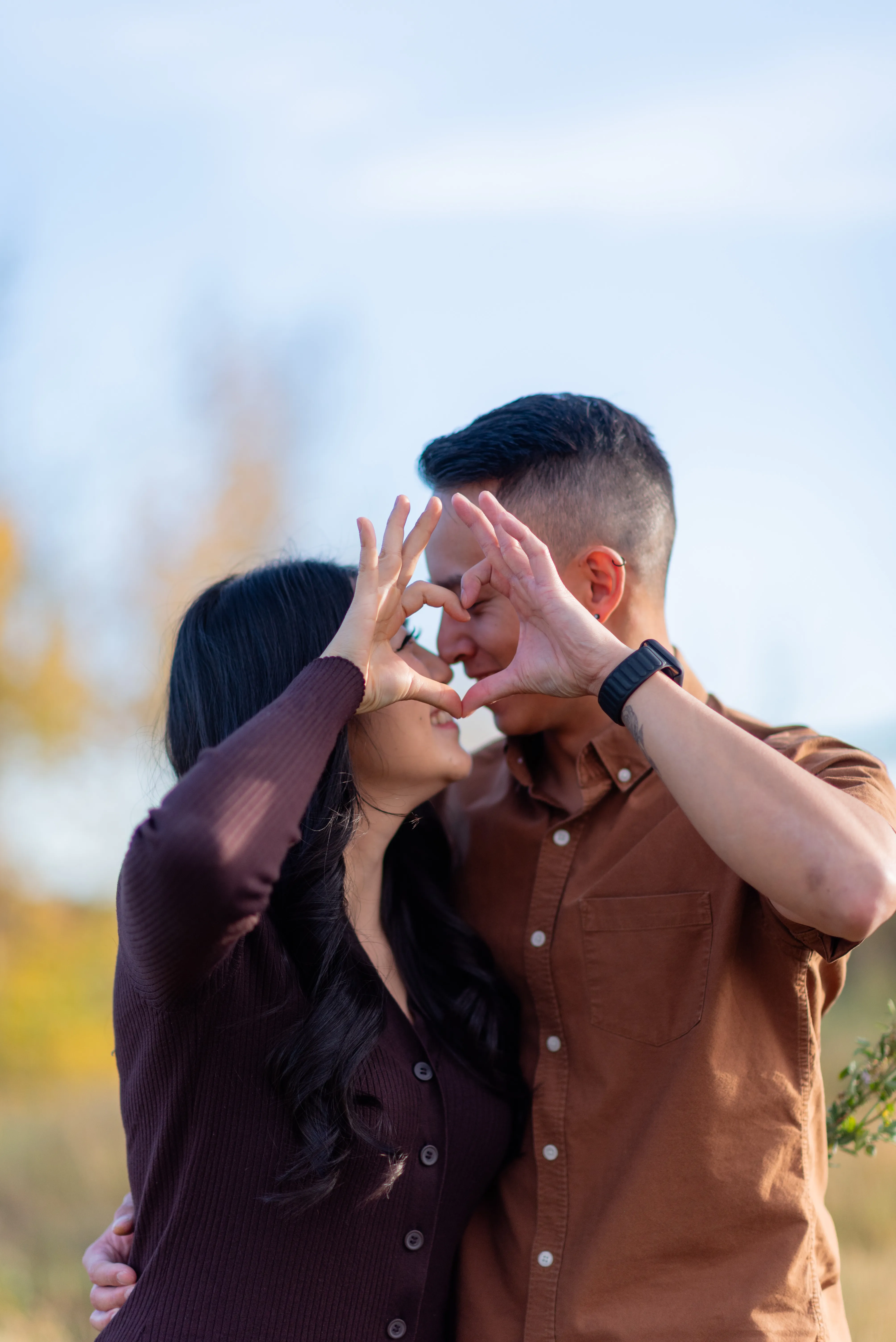 A couple holding up a heart sign as they kiss at Evamy Ridge Calgary