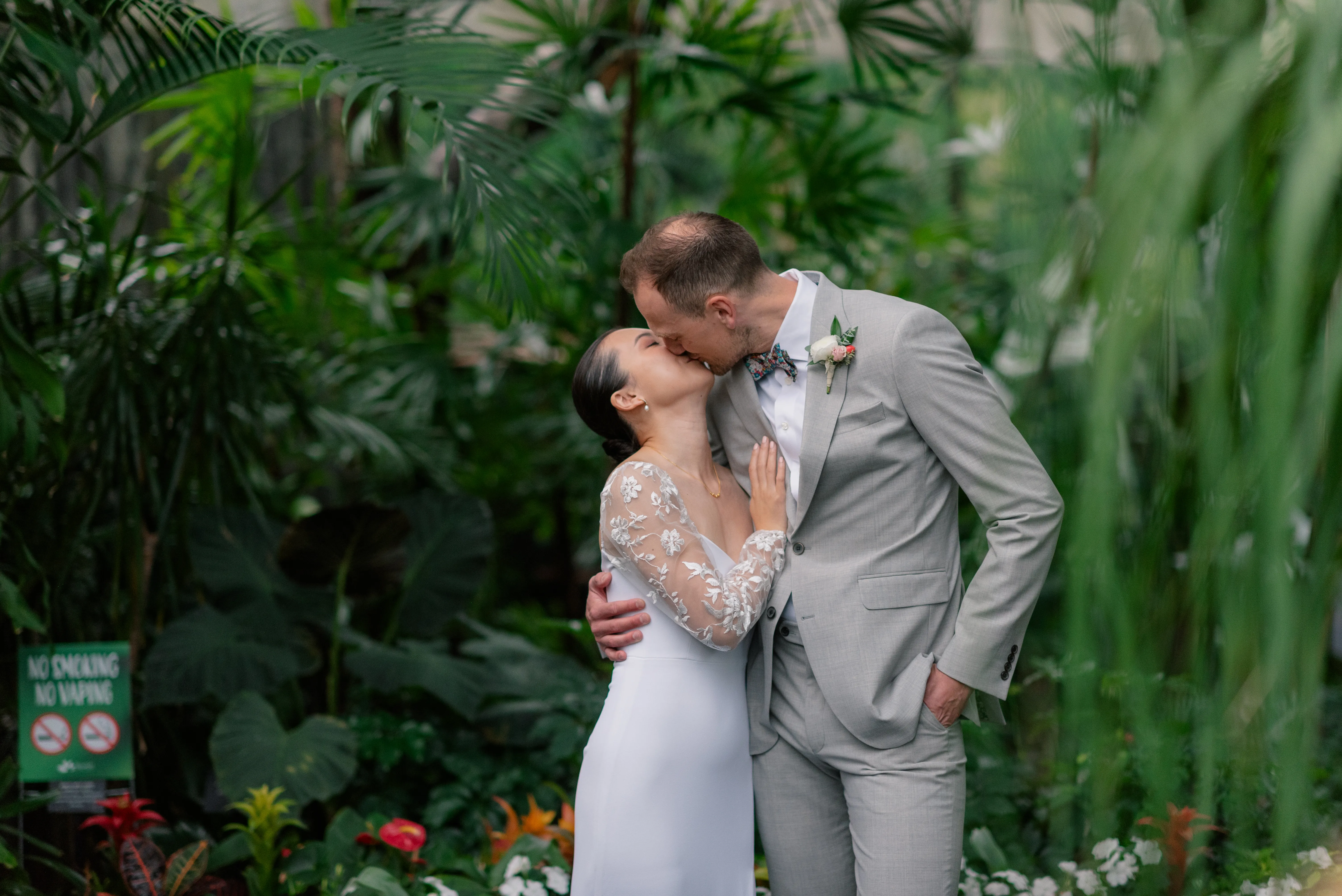 Bride and groom embracing among the tropical plants inside Bloedel Conservatory, surrounded by lush greenery