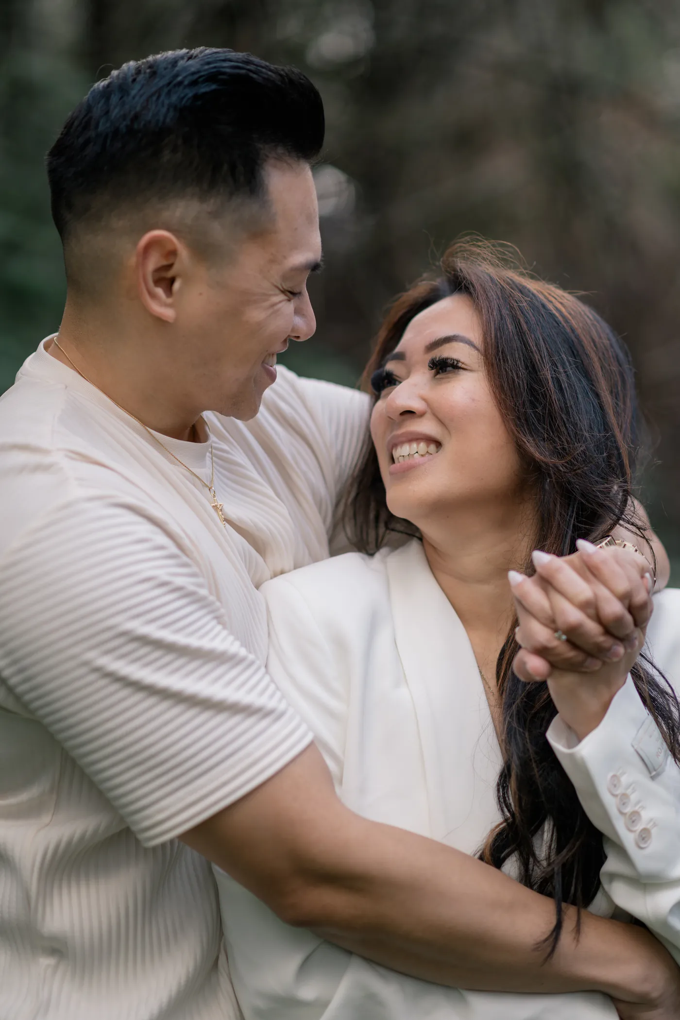 A couple sharing a warm embrace in the woods of Stanley Park during their romantic Vancouver engagement session.