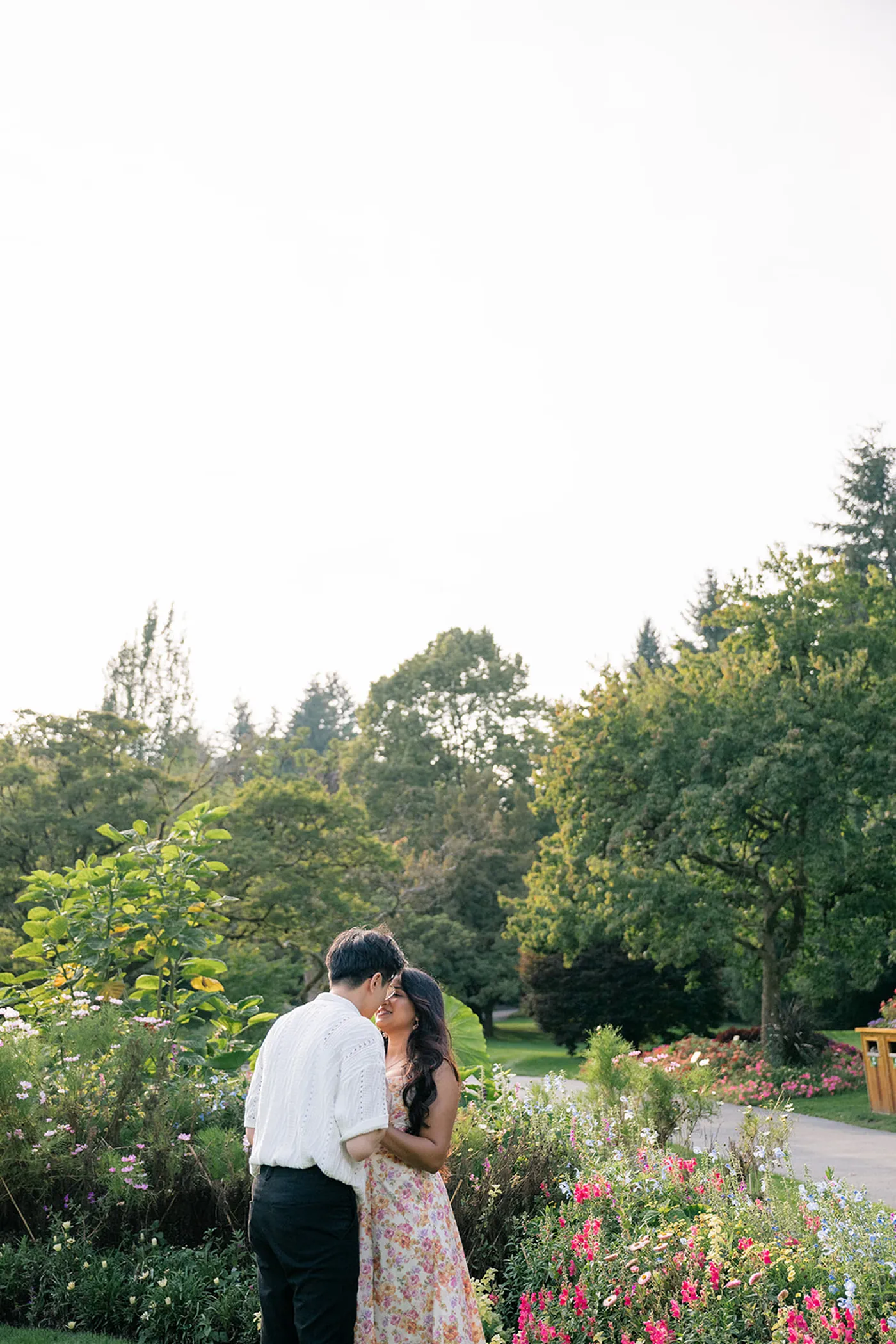 Couple sharing a romantic moment under the tall trees at VanDusen Botanical Garden after their proposal.