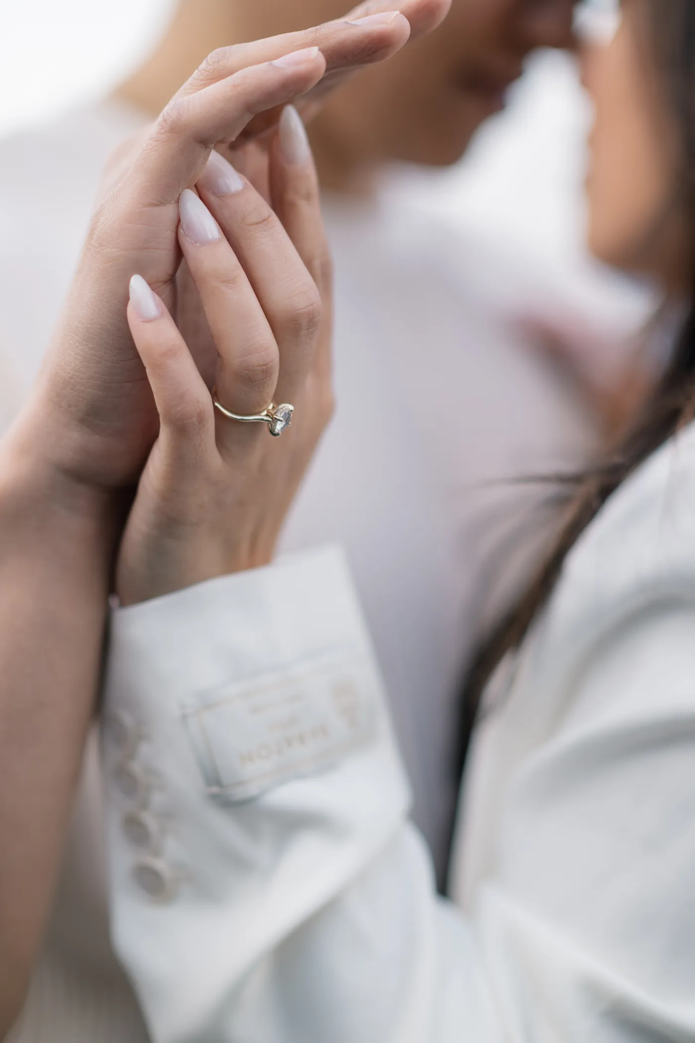 A close-up of a couple’s hands intertwined, highlighting their elegant attire and engagement rings
