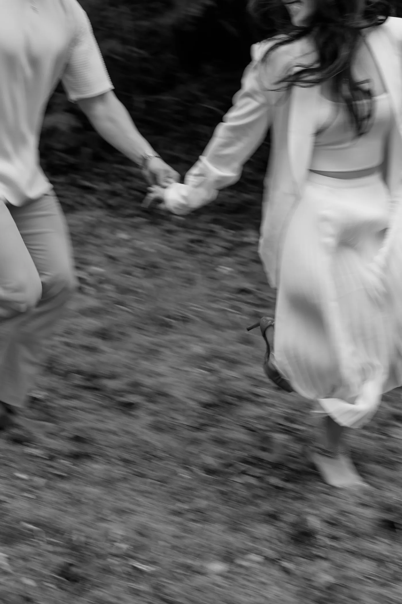 A black and white photo of a couple running through the park, full of energy and joy.
