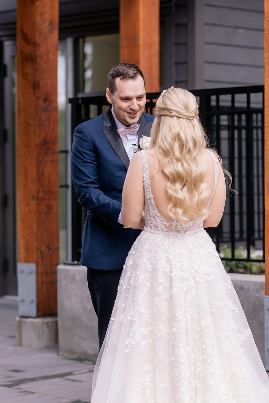 Bride and groom holding hands, sharing a tender and emotional first look moment.