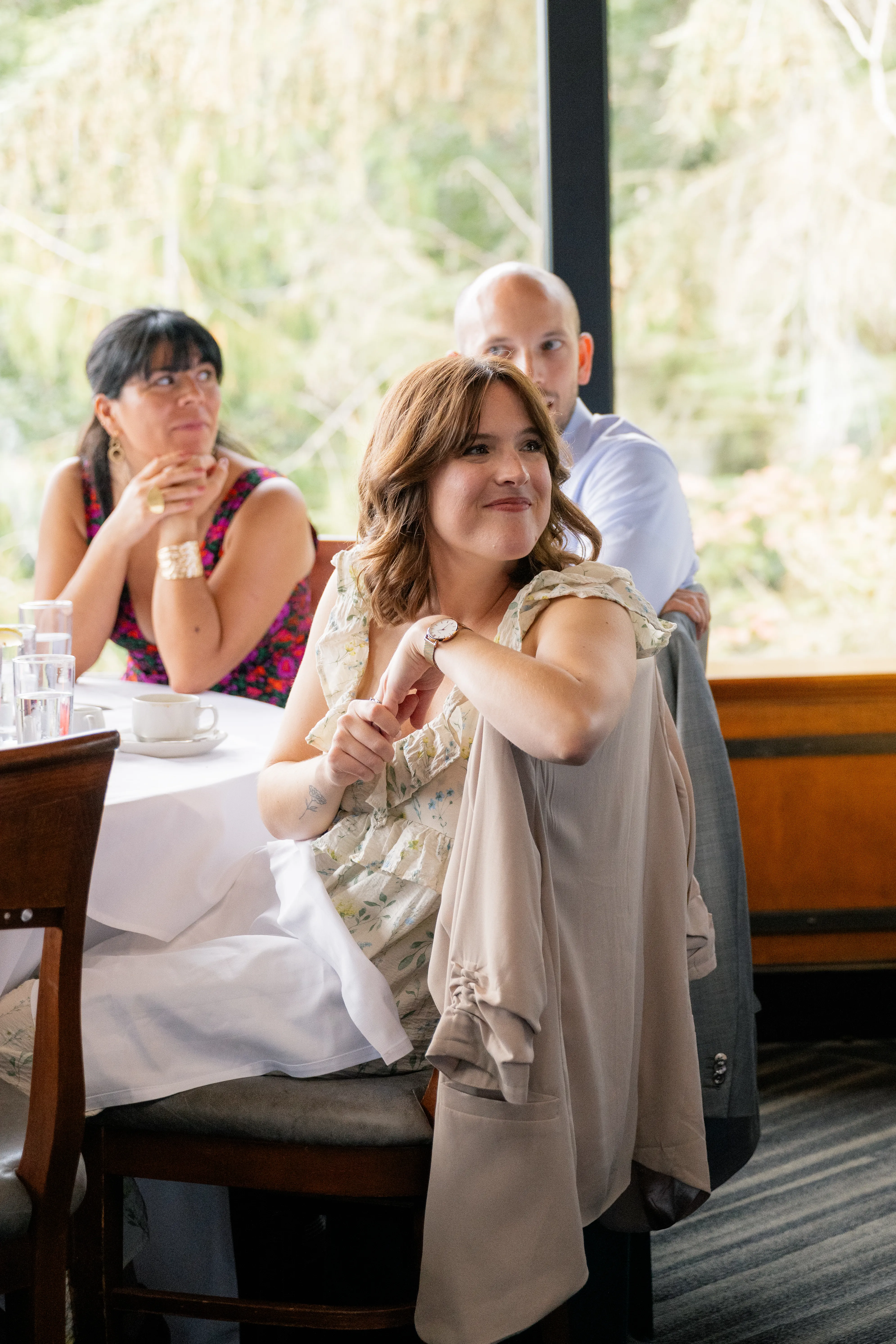 Woman sitting at a table, appearing emotional and holding a tissue to her face during the wedding reception.