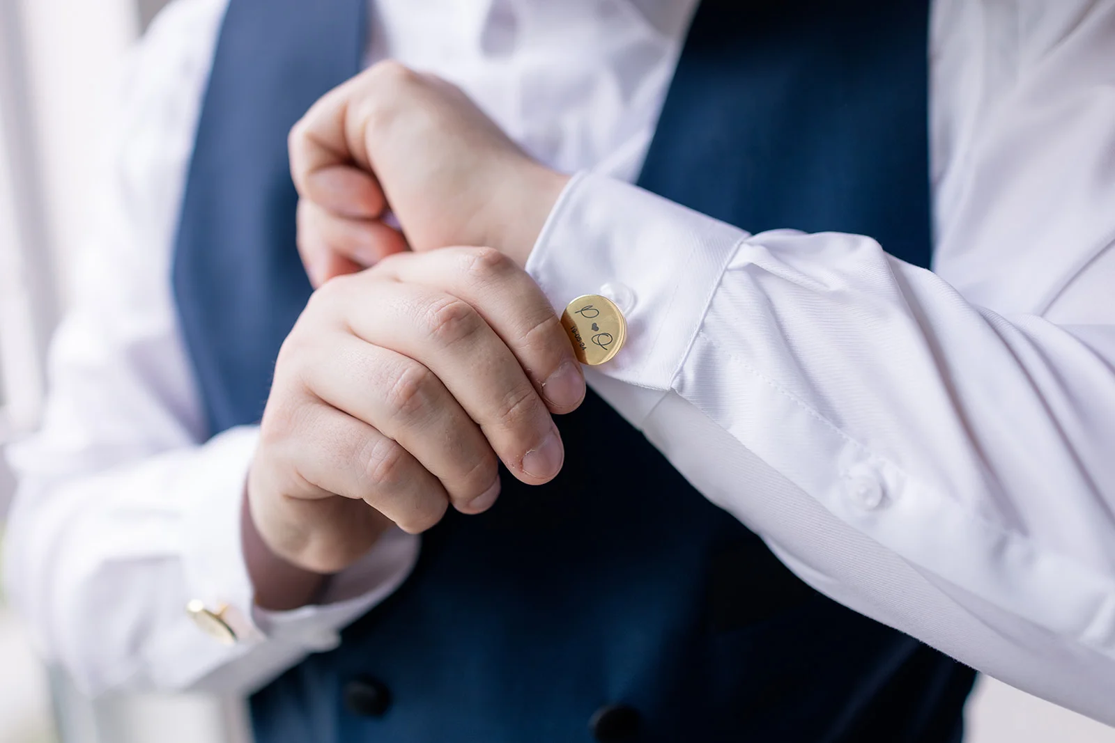 Close-up of the groom fastening his cufflinks, adding a personal touch to his wedding attire