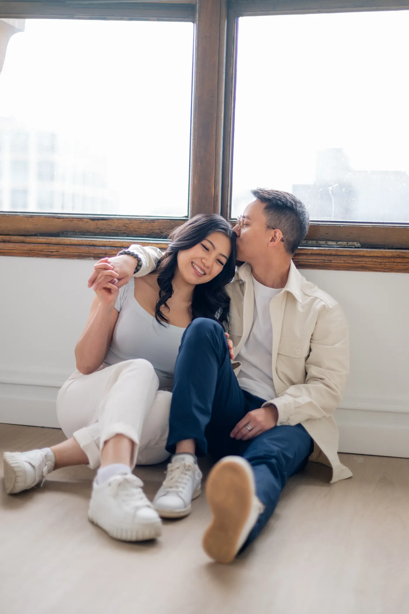 Vancouver engagement photoshoot in The Covet Studio featuring a cozy embrace with elegant arched windows in the background.