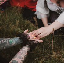 A tattoed fae receiving small resin babies from a burly wench