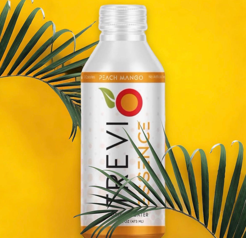 Trevi Essence Water can in front of palm trees