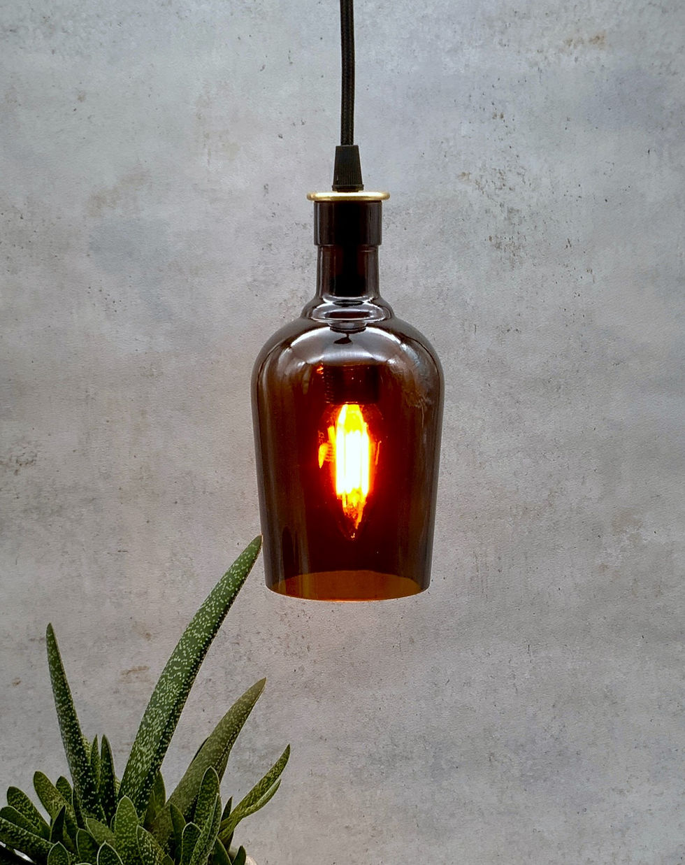 Upcycling Lampe - kleine braune Gin-Flasche mit einem schwarzen Kabel und einem Messingabschluss