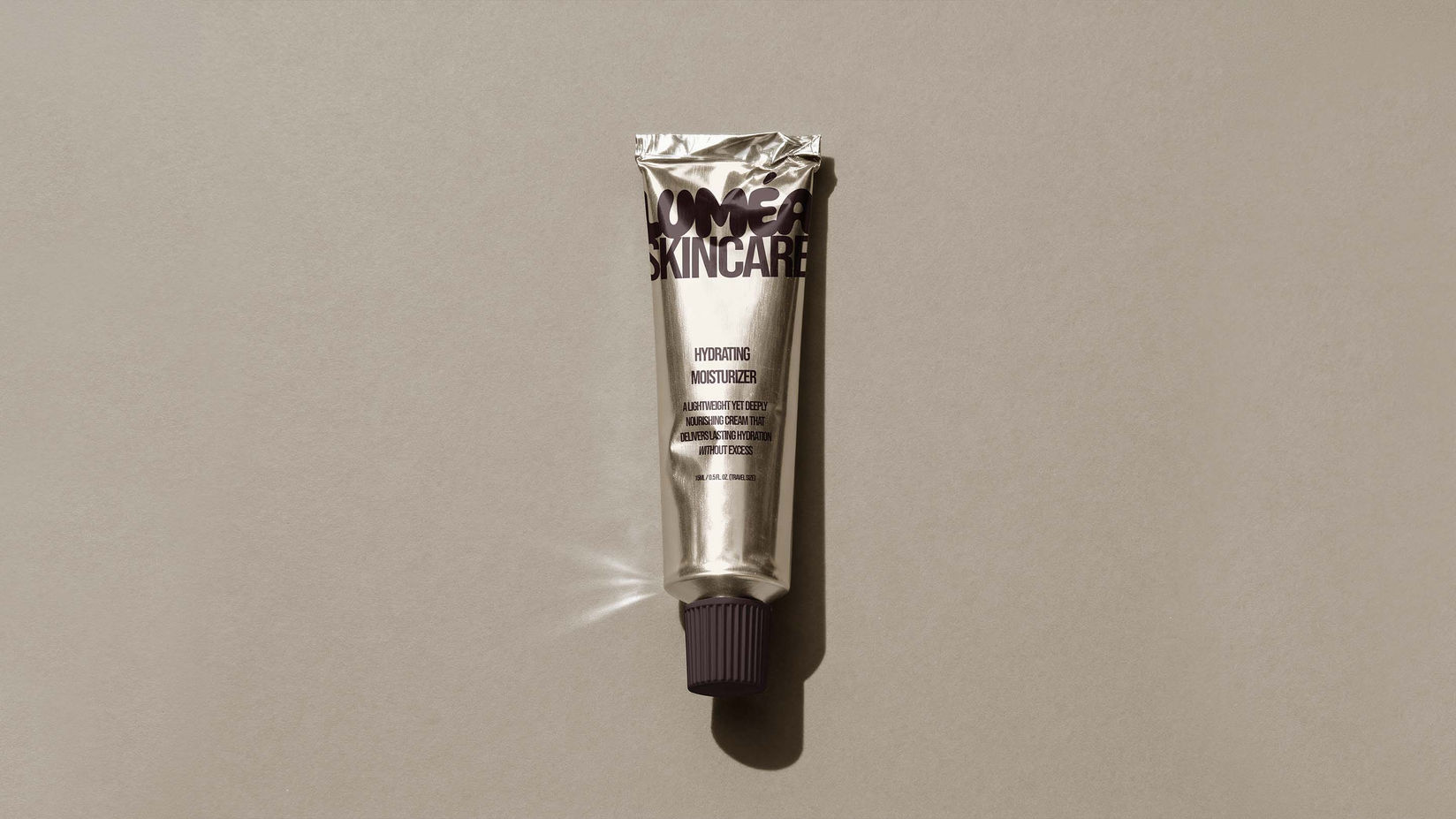 Luméa Skincare hydrating moisturizer gold tube on neutral background — luxury skincare packaging design by Studio Ruby Signorelli