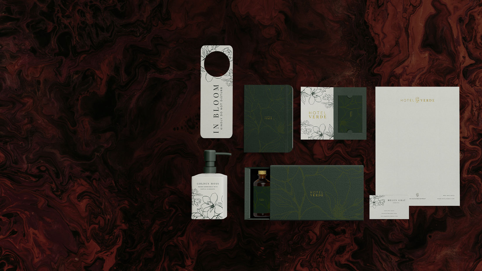Various hotel stationary with 'IN BLOOM' text displayed on dark red background