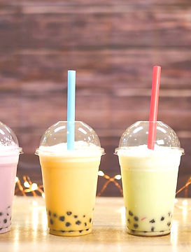 Four different flavors, sealed plastic cups, with colorful BOBA Bubble Tea drinks sitting side by side, illuminated by a string of white lights.