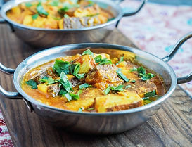 Paneer-Korma-A serving of paneer tikka masala in a silver bowl next to another bowl of the same dish on a table.