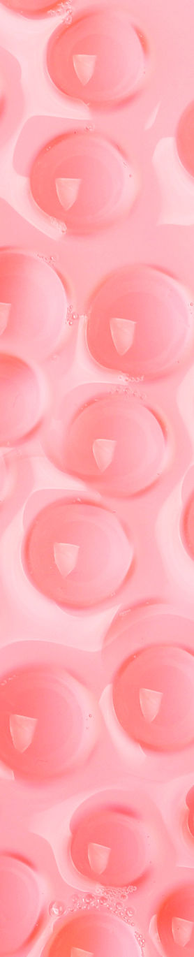 Pink Bubble TeaTiny pink bubbles float on the surface of a clear liquid, appearing pink, in a close-up image with a soft-focus background.