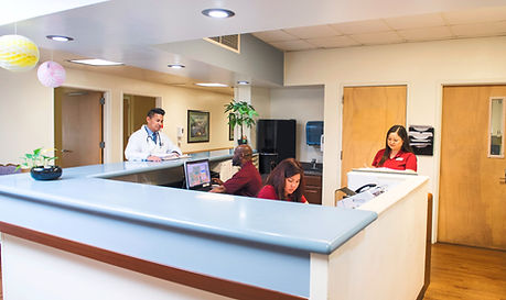 In a modern medical clinic, a diverse group of healthcare professionals work together at the reception desk, ready to assist patients.